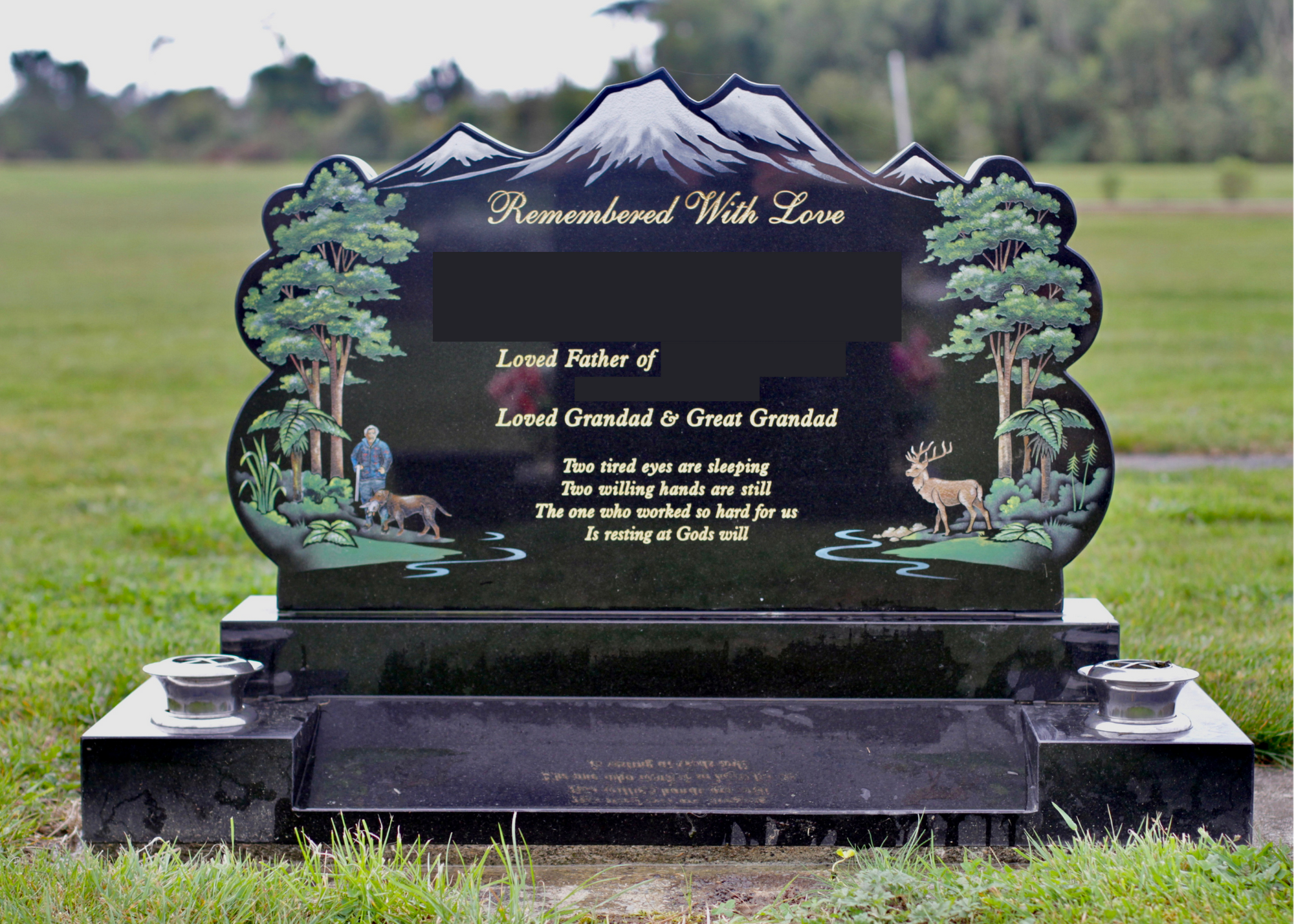 Black granite gravestone with painted mountains and trees, a man with a dog, and a deer in a forest scene. The grave has the inscription "Remembered With Love" and a poem dedicated to a loved father, granddad, and great-grandad.