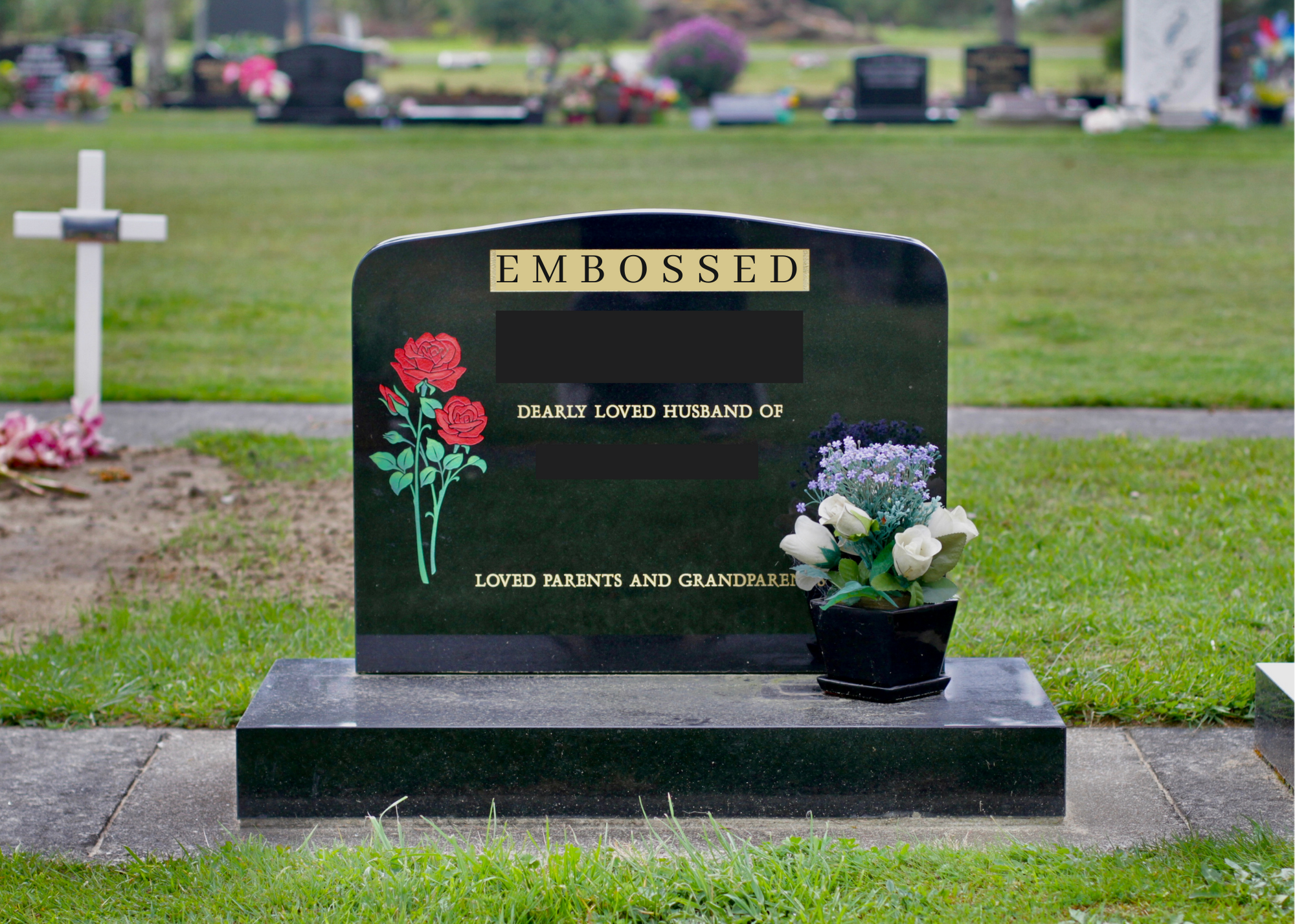 A black granite gravestone with the word 'Embroidered' at the top, decorated with painted red roses and green leaves on the left, and a small black pot with white and purple flowers placed on the right side, in a cemetery with other gravestones and crosses in the background.