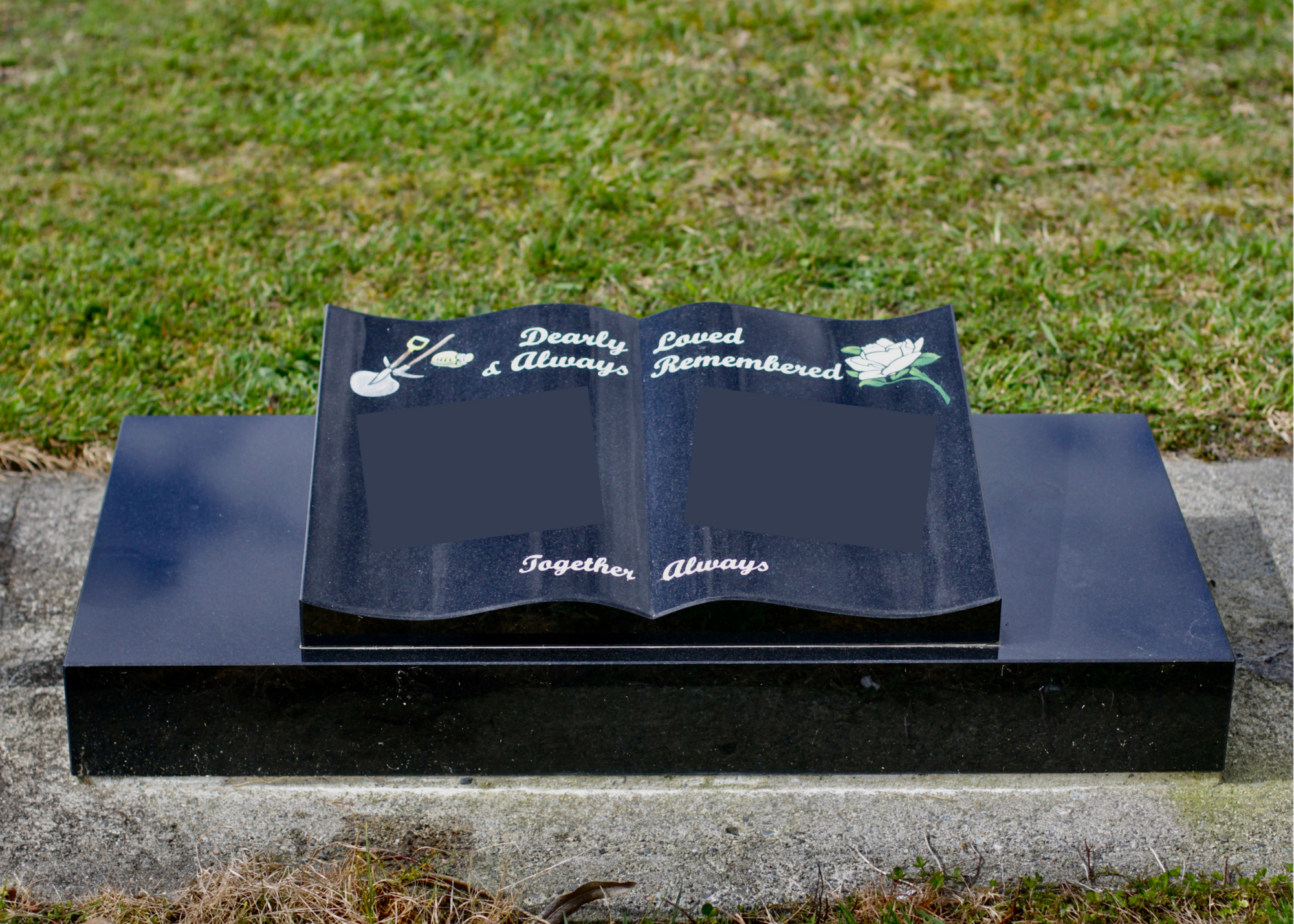 Memorial plaque with engraved text on a black stone in a grassy area.