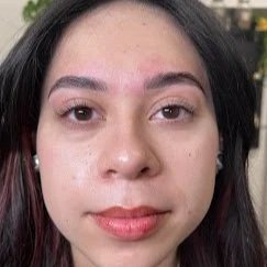Close-up portrait of a young woman with dark hair and light makeup, with a neutral background. lash lift and brow lamination