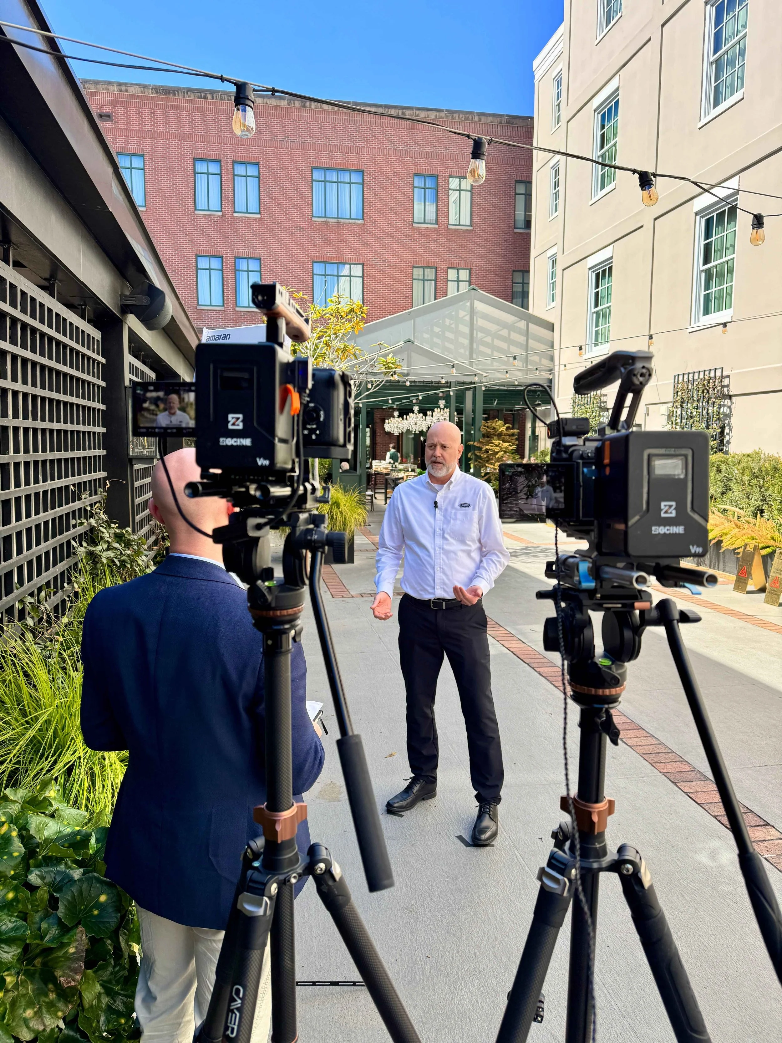 Outdoor interview video production with multiple cameras filming a speaker at an industry event