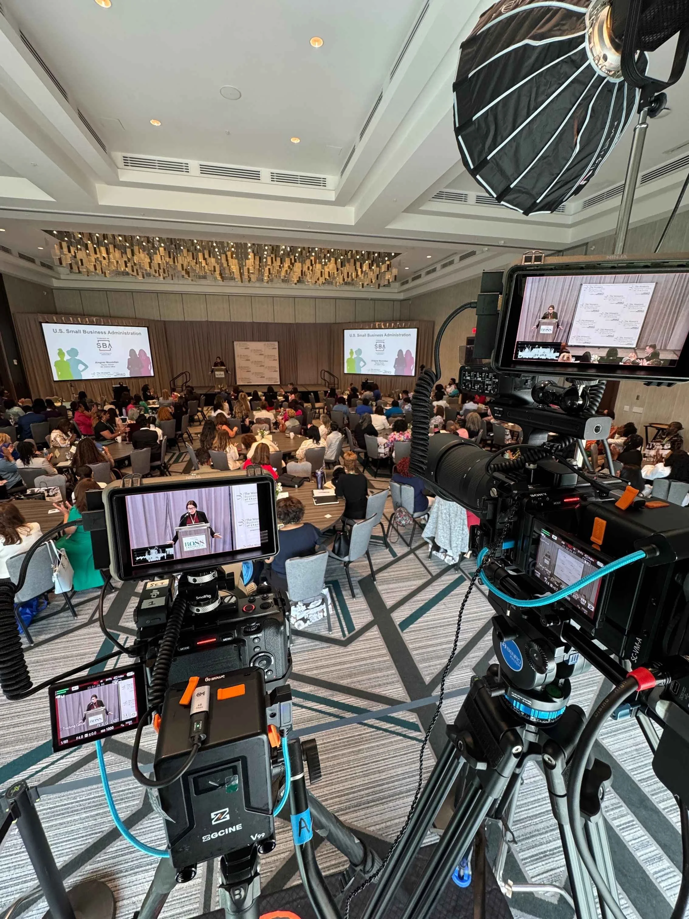 Conference video production setup with multiple professional cameras filming a live industry event