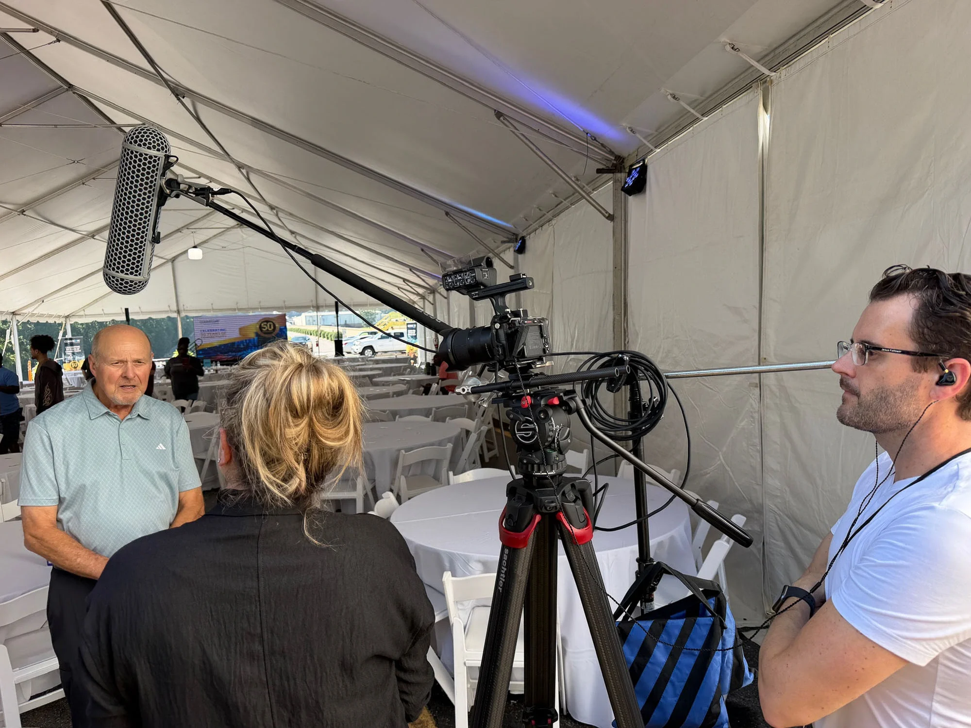 On-location interview filming at CommScope’s 50th anniversary celebration with camera, boom microphone, and lighting setup.