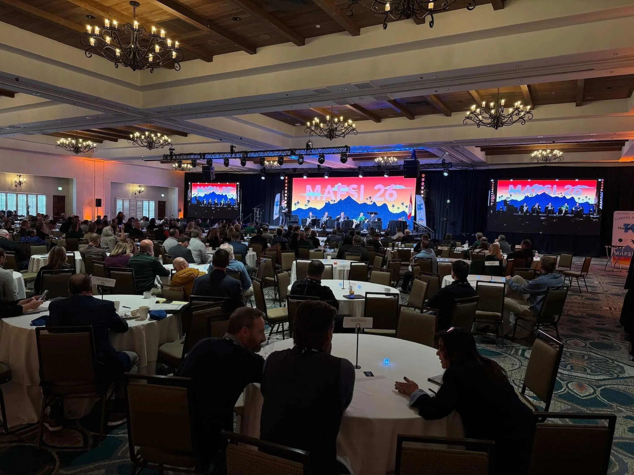 Large industry conference with attendees watching a keynote presentation during a professionally produced live event