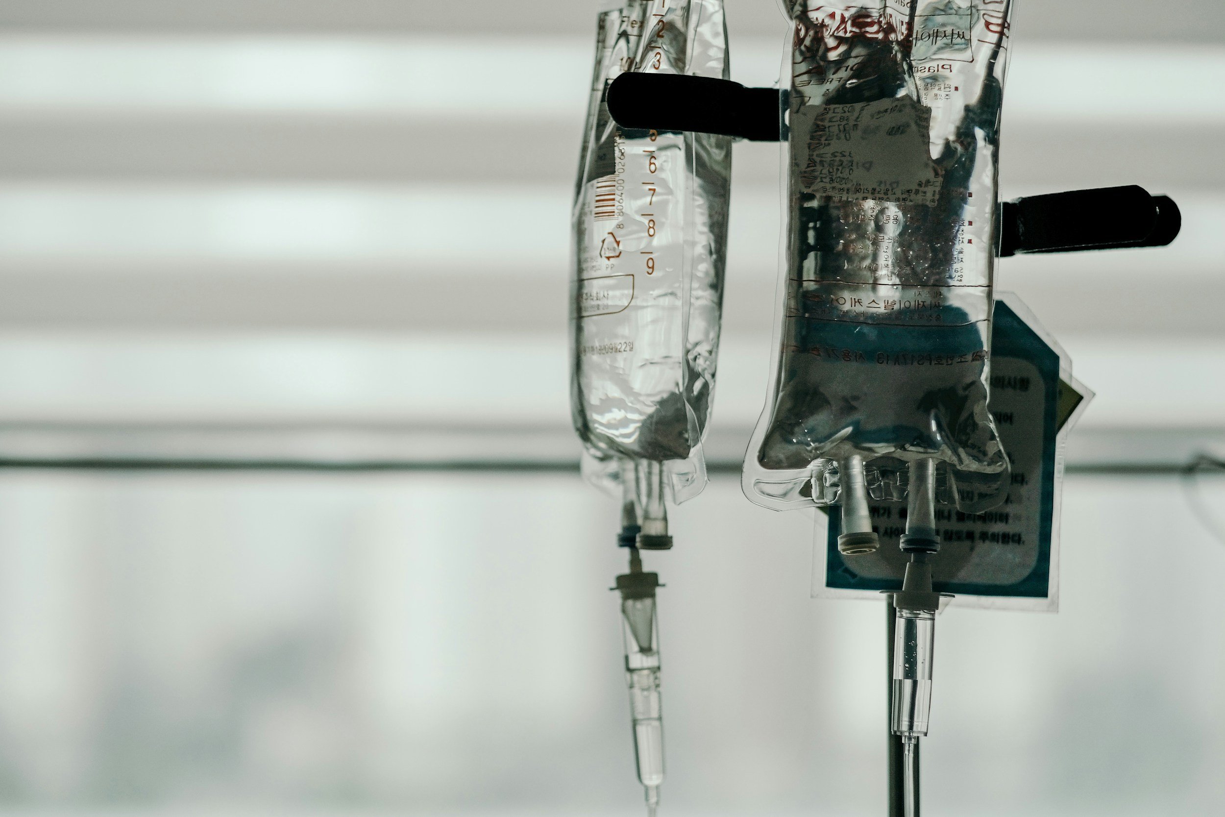 IV drip bags hanging in a medical setting.