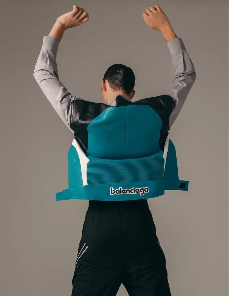 image of a male model facing backwards wearing a balenciaga shirt with a moto jacket patch on the back in teal