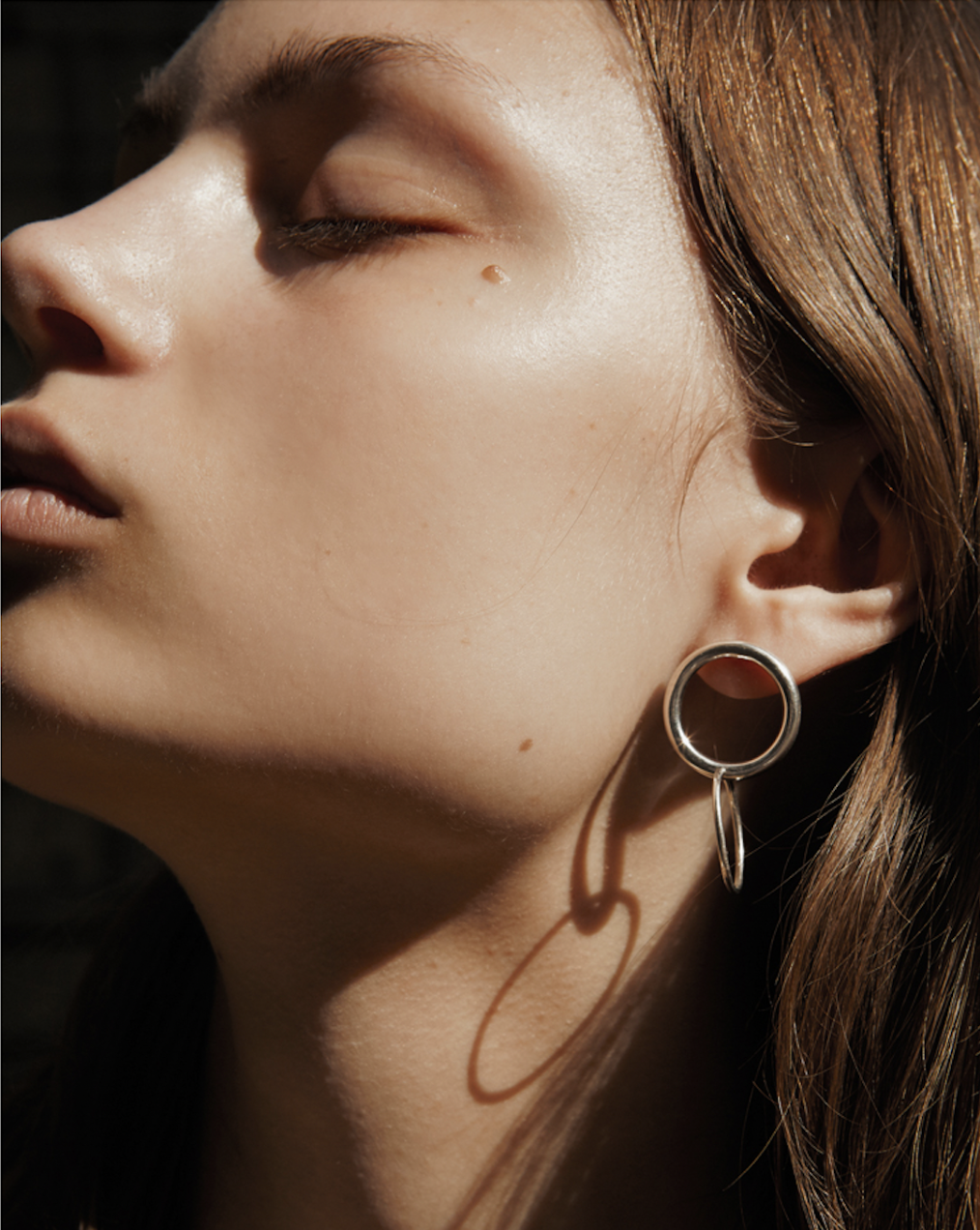 close up of a swedish female model wearing an earring of two connected circles