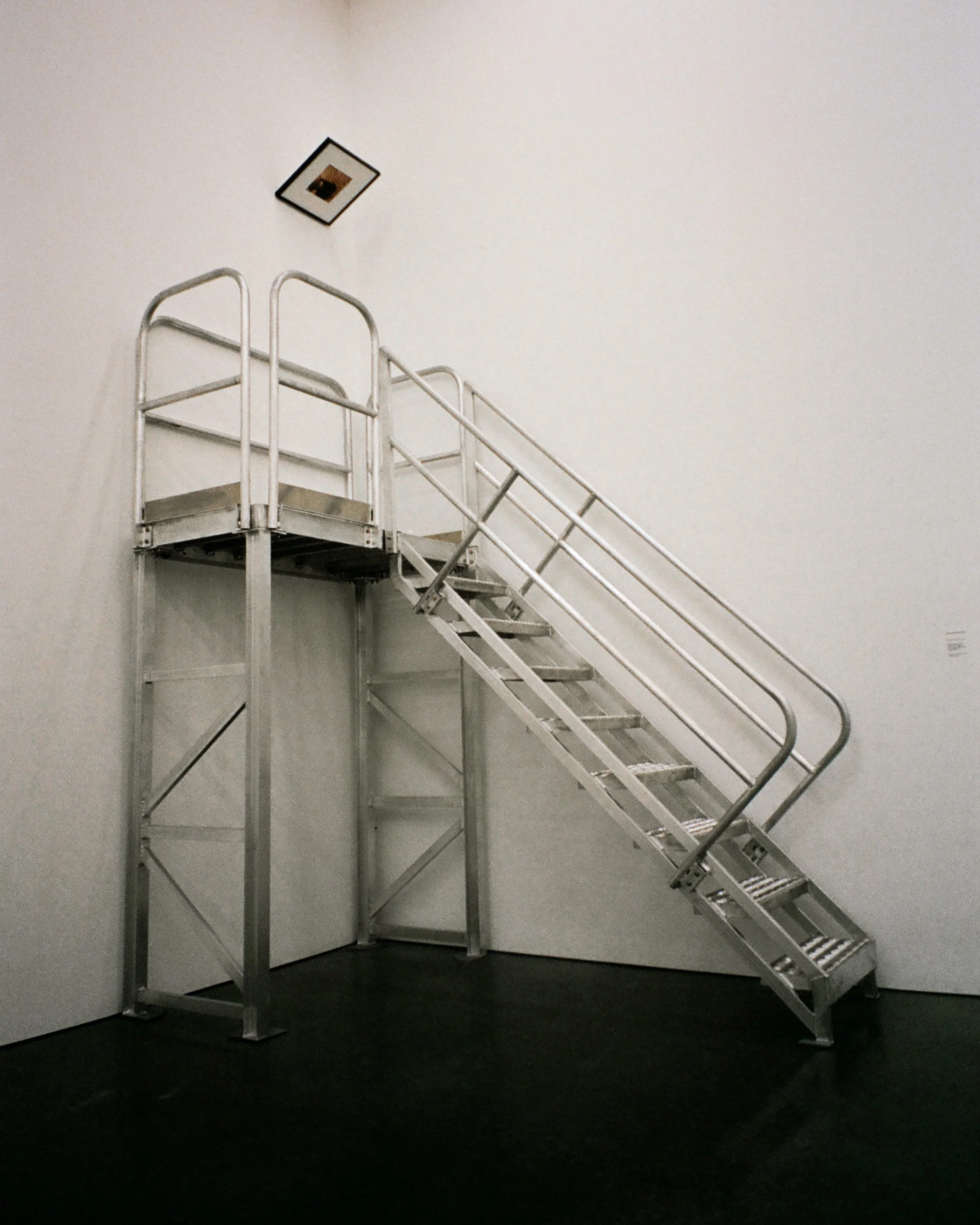 photo of a metal staircase that leads to a portrait of an artist in a white room at the Parrish Museum in the Hamptons, NY