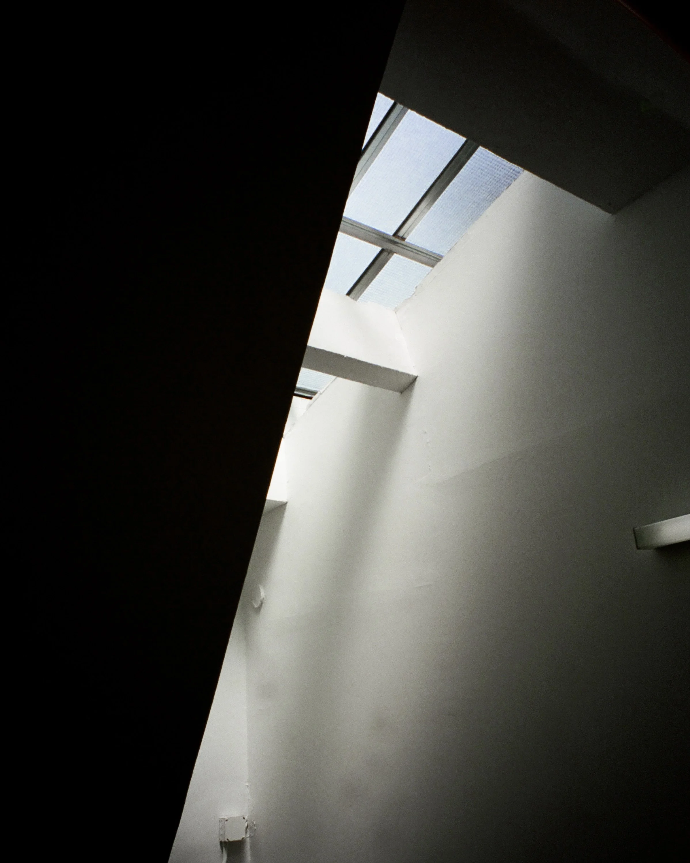 Photo of light streaming down through a skylight in a white stairwell