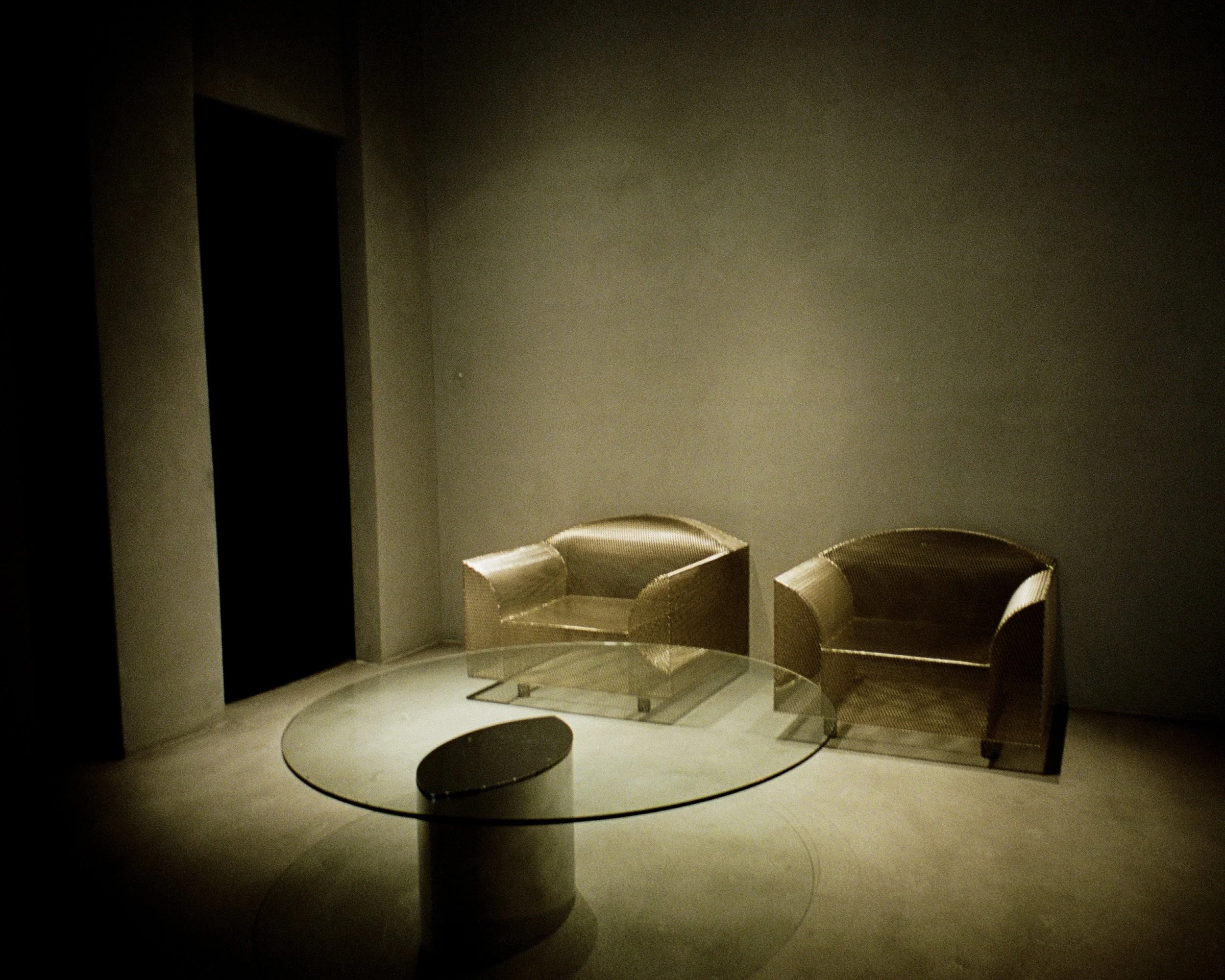 Two metal mesh chairs and a glass table at the Khaite store in SoHo