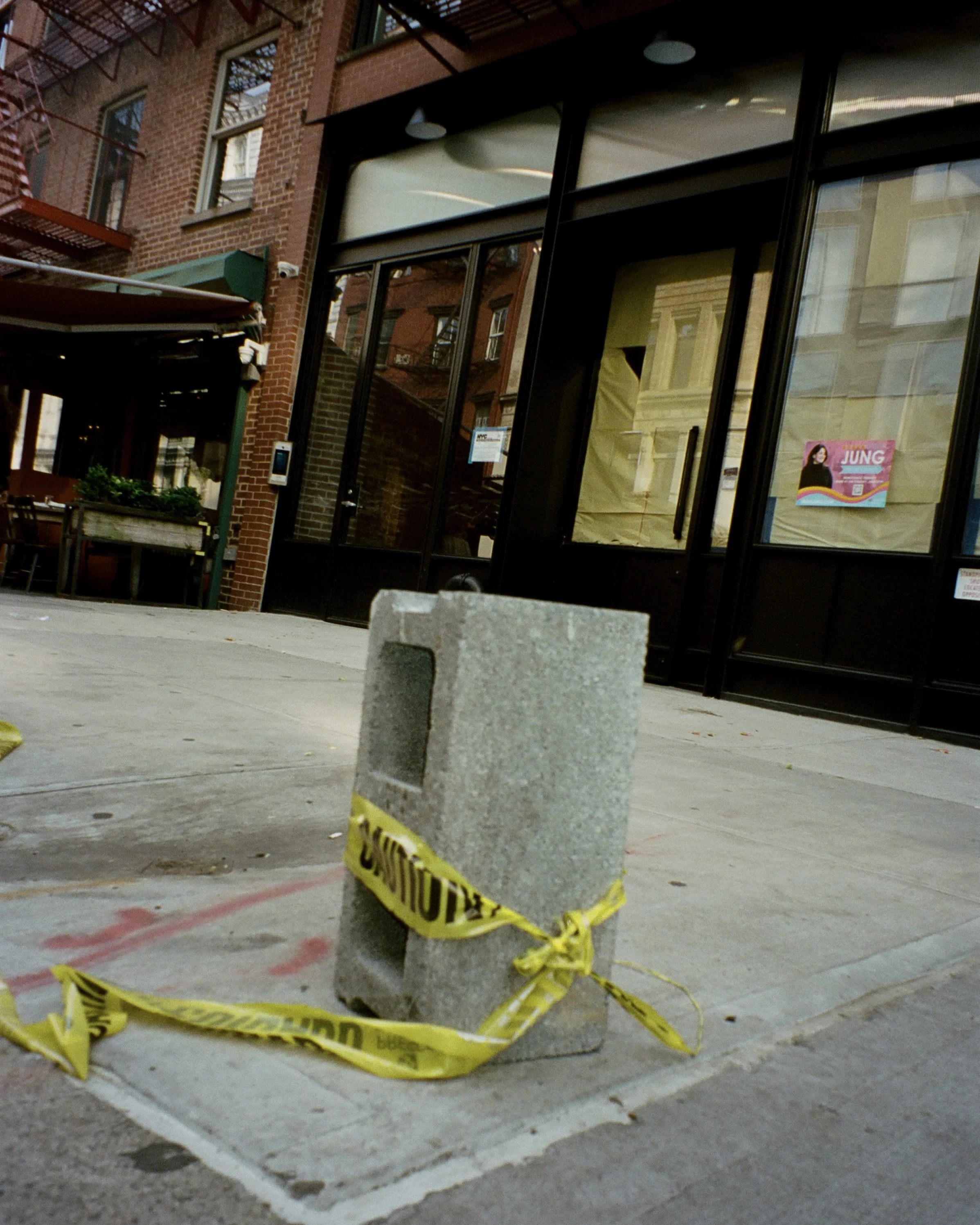 A photo of a cinderblock on the street wrapped in yellow caution tape