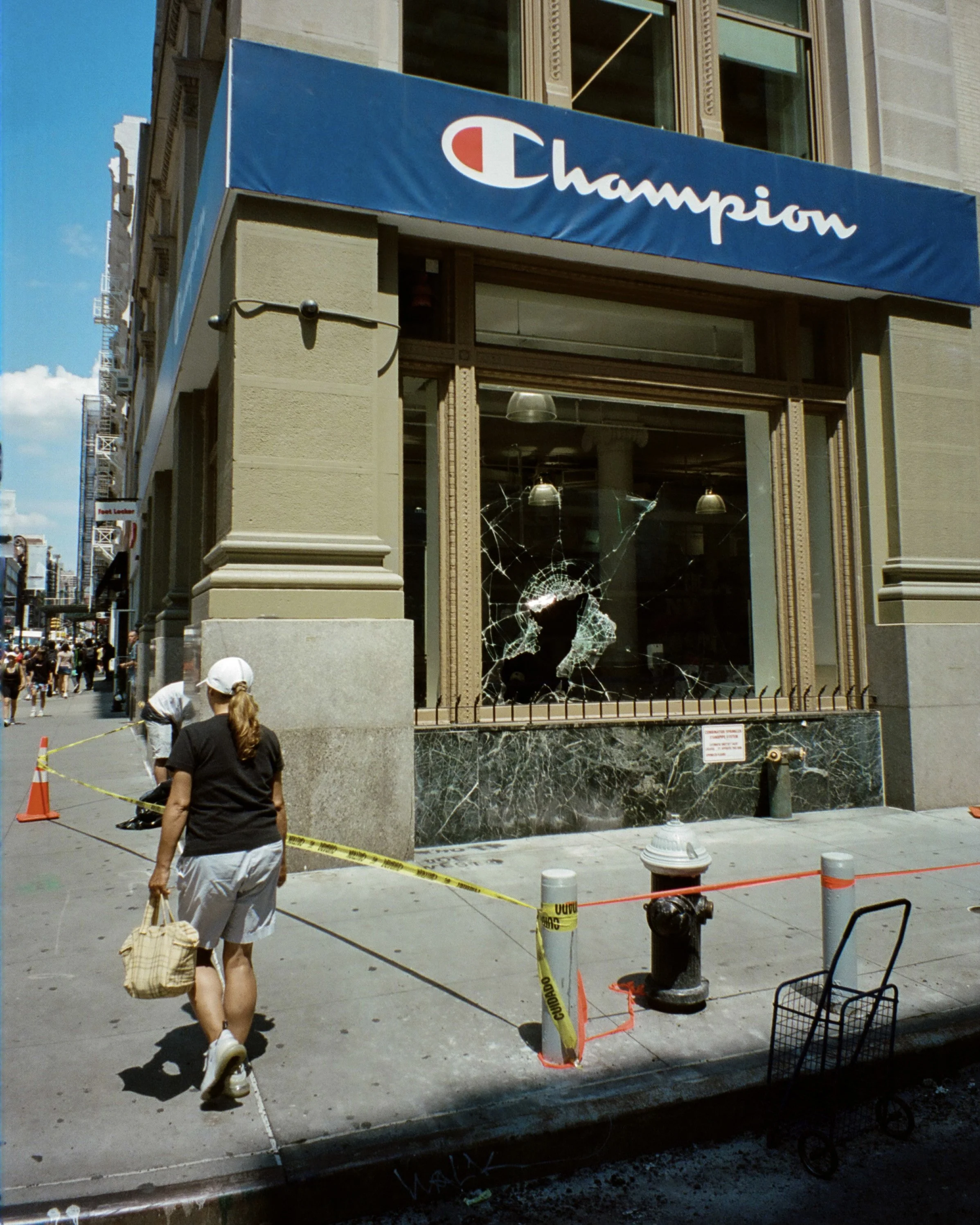Photo of a woman looking at the broken front window of a shopping store