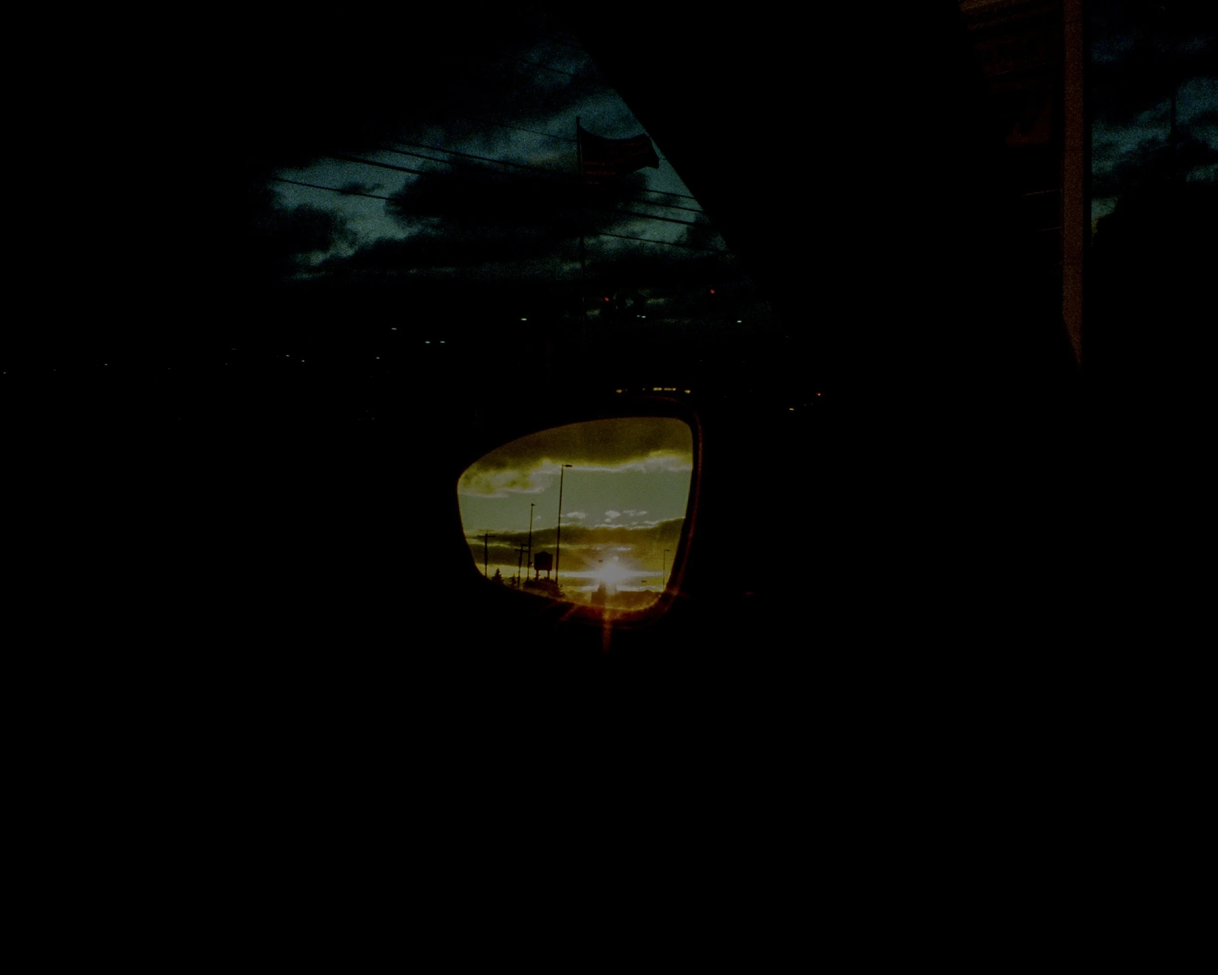 The sunset in the reflection of a rearview mirror