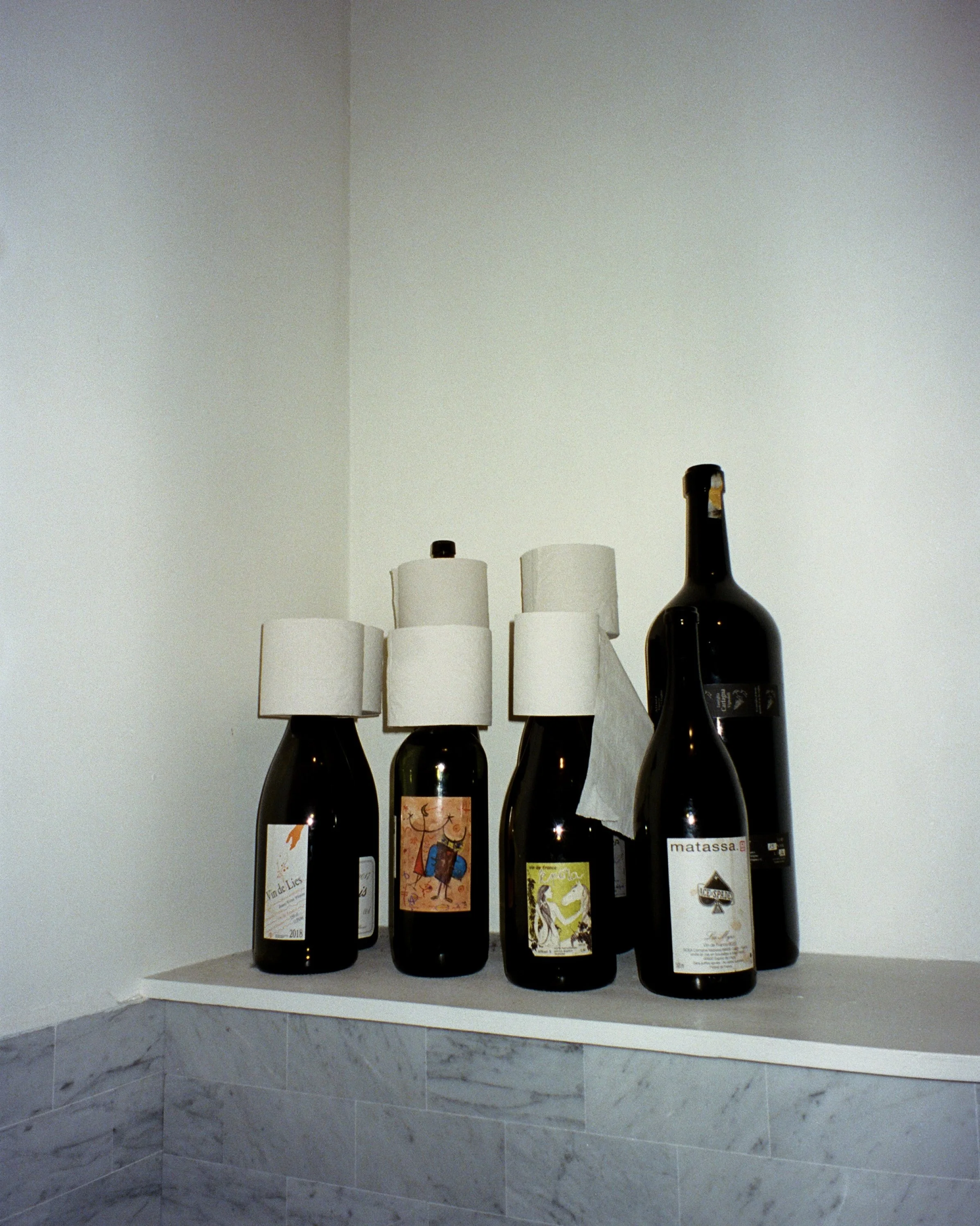 Wine bottle necks being used as toilet paper holders