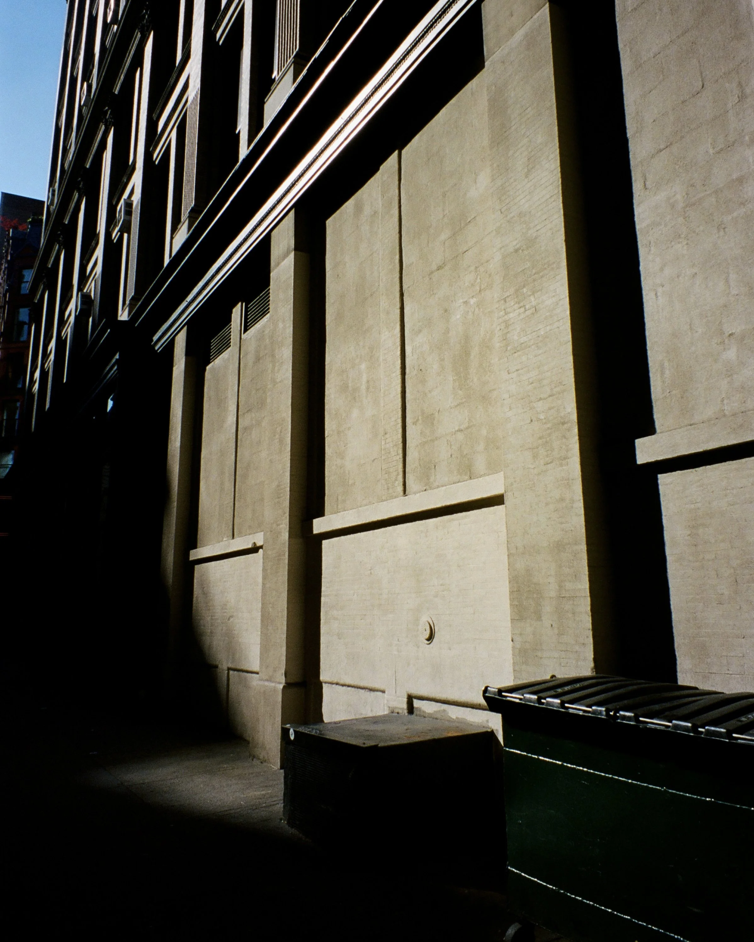 The sun shining dramatically on the side of a cement building