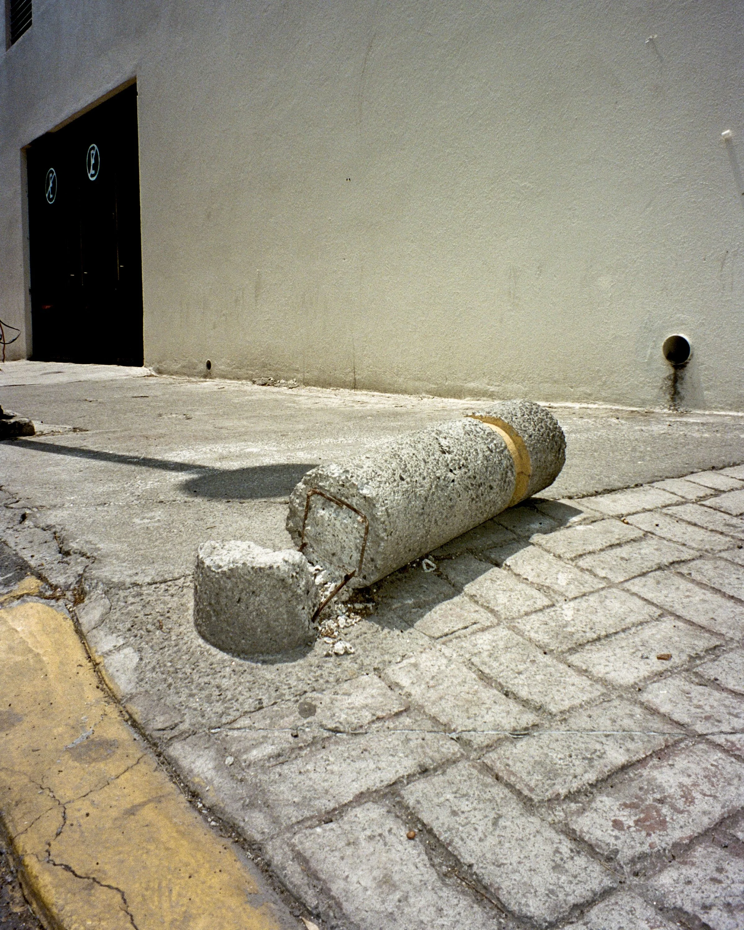 A broken cement safety pole on the sidewalk