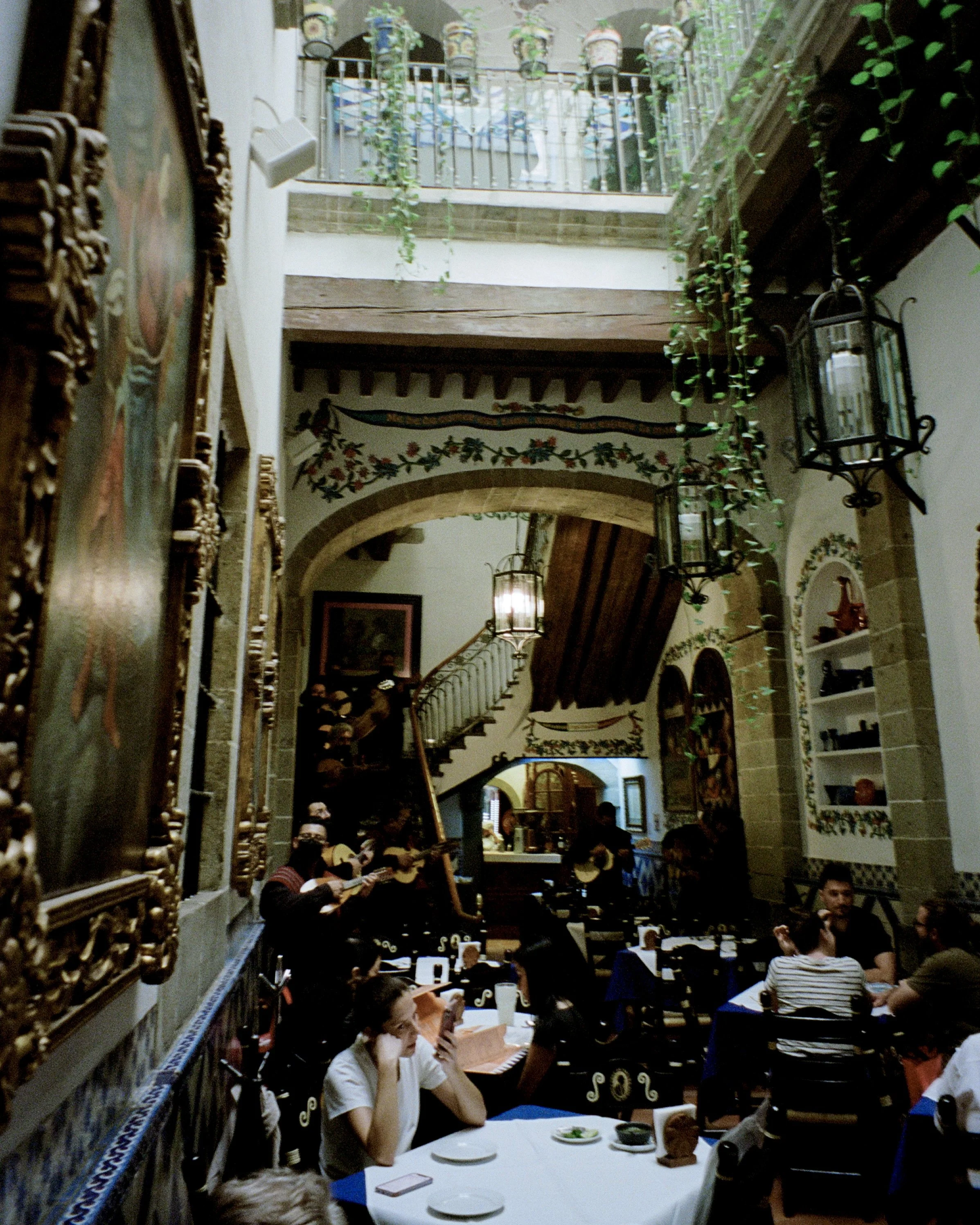 A traditional Mexican restaurant with plants and people eating at tables