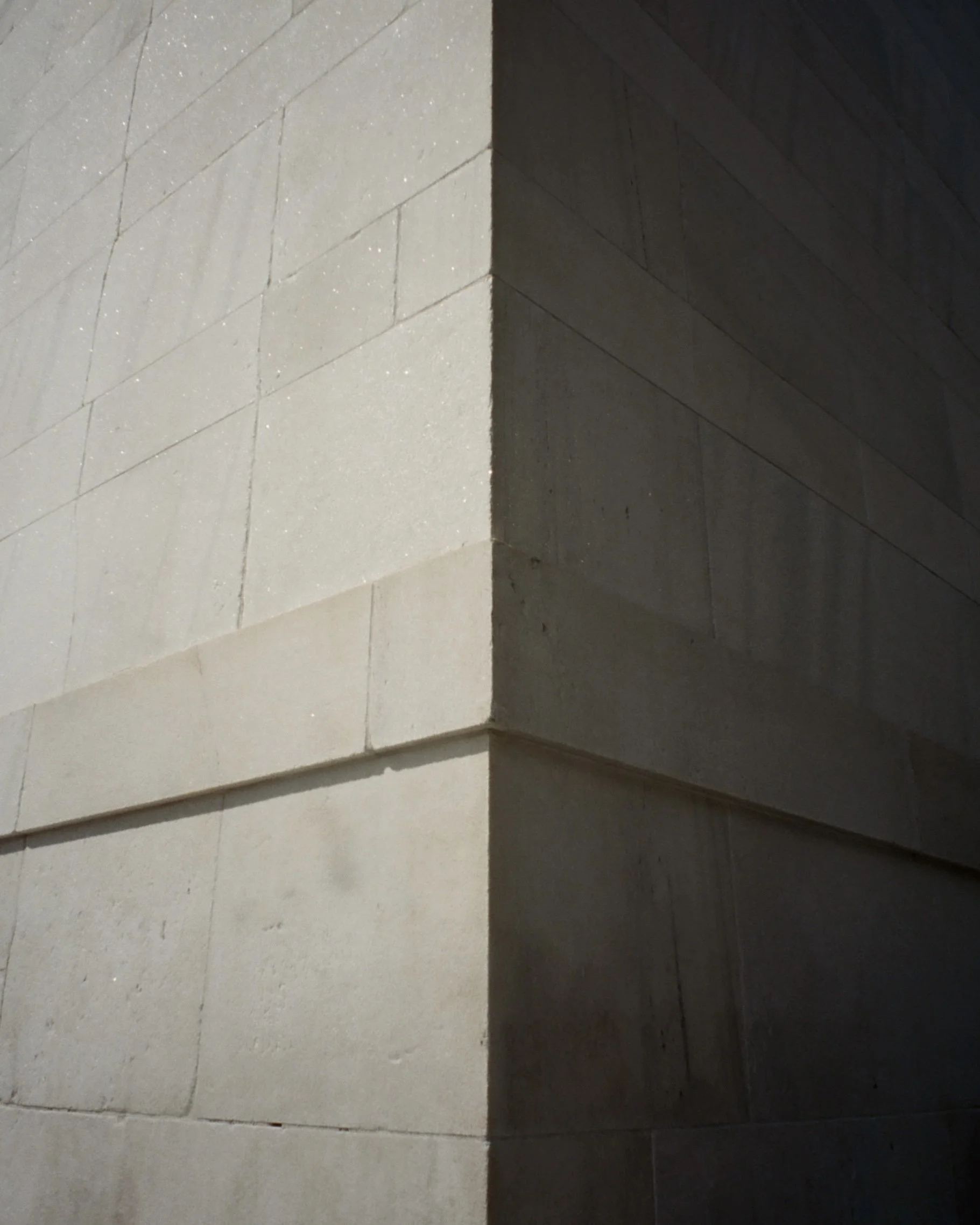 Photo of the corner of a building where one side is lit by sunlight and the other side is in the shadow