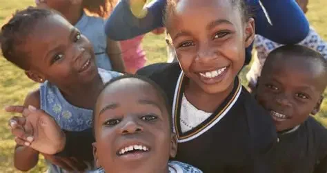 A group of smiling children outdoors, looking at the camera.