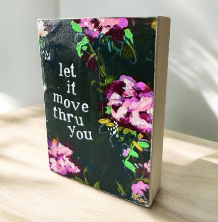 A small decorative book with a floral cover and the words 'let it move thru you' printed on the front.