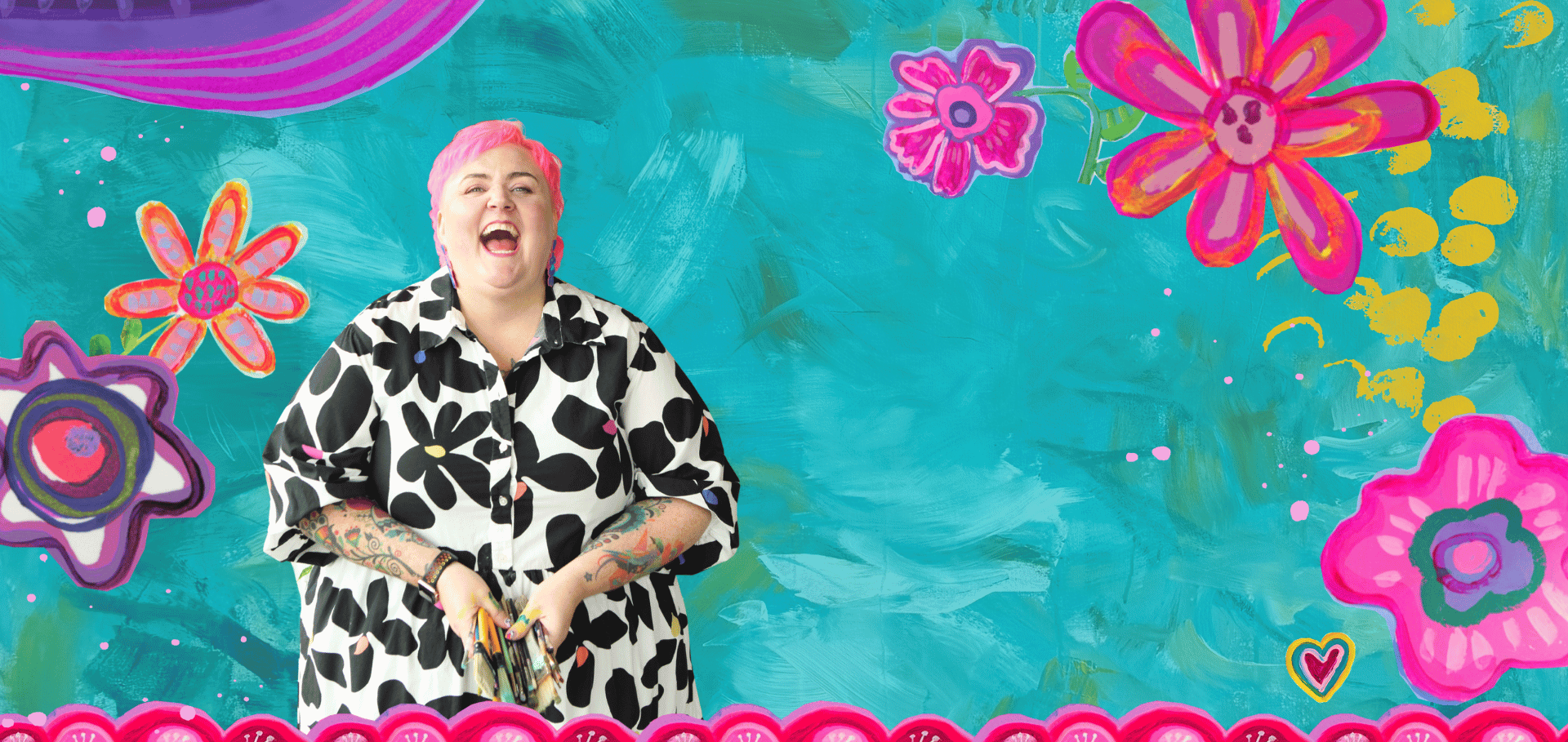 A woman with pink hair and tattoos on her arms is laughing, dressed in a black and white floral print shirt, standing in front of a colorful, abstract floral background.