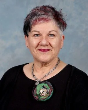 Amanda Rowarth wearing a black top and a silver necklace, smiling against a plain background.