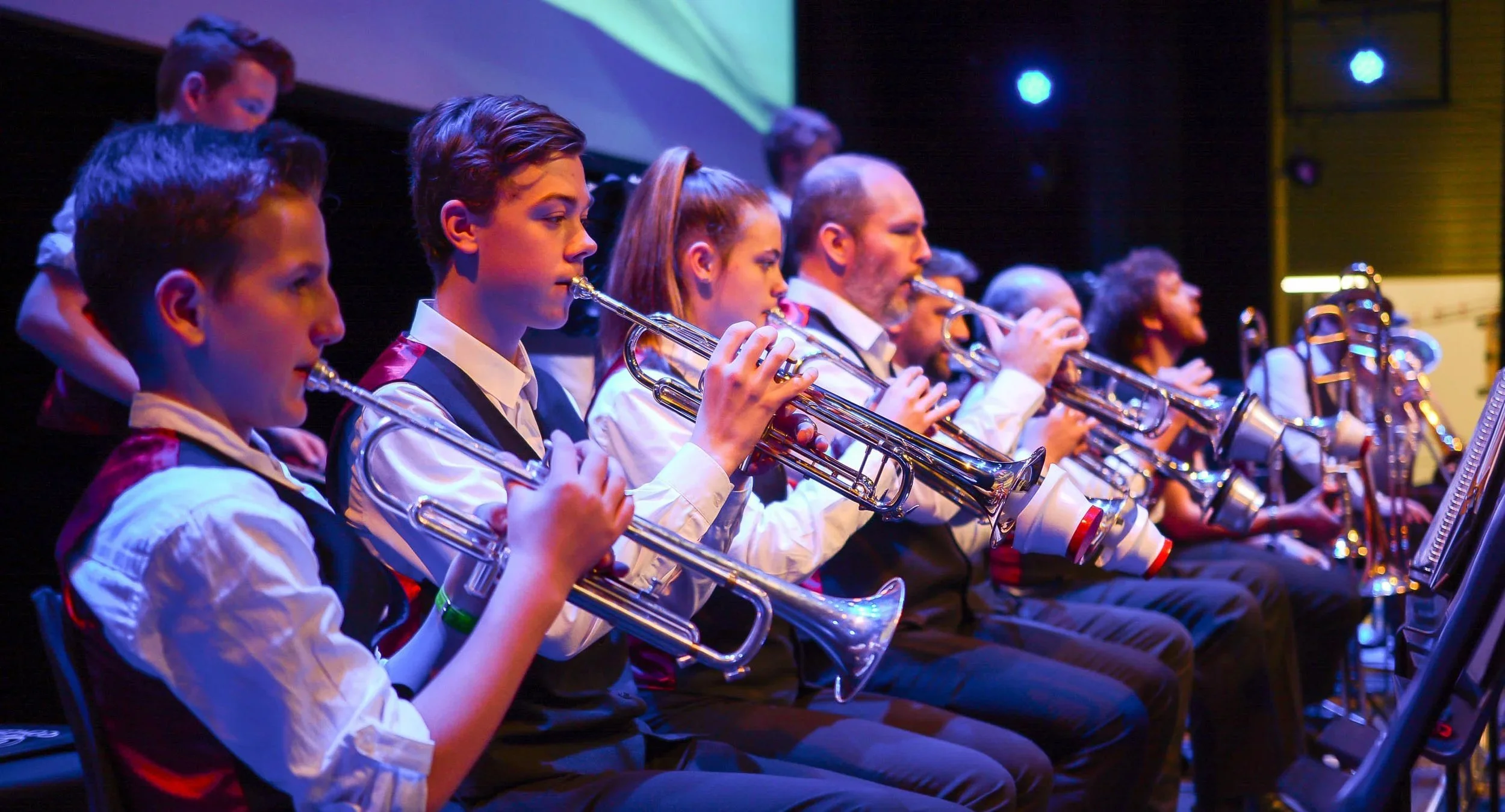 A group of young musicians playing trumpets on stage during a performance.