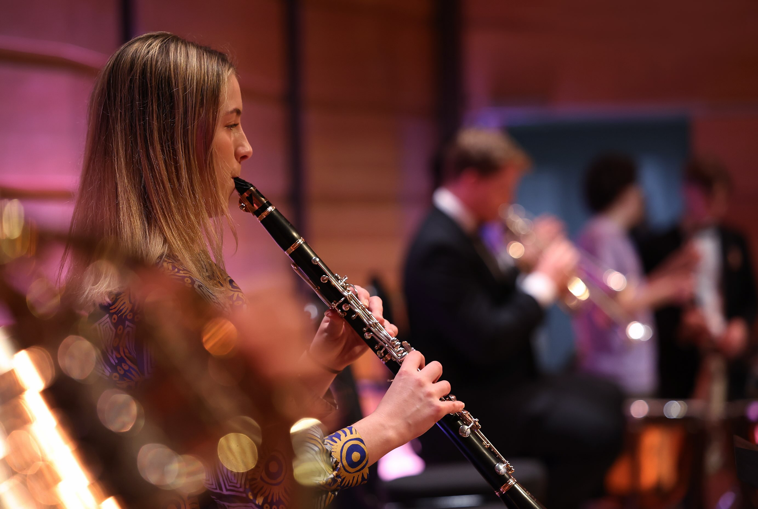 Jorja Withall playing the clarinet in a concert with other musicians in the background.