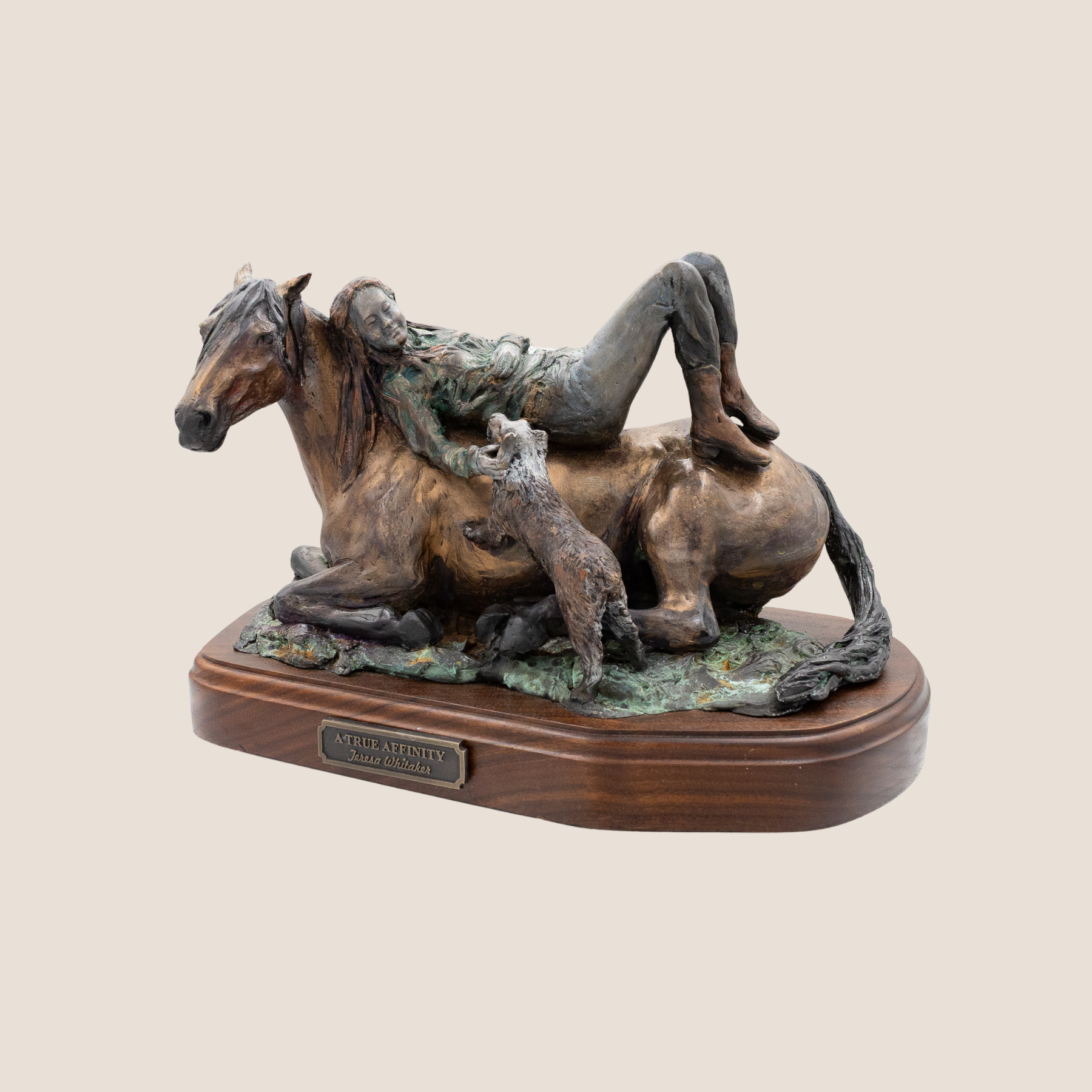A bronze sculpture titled 'A True Affinity' depicting a girl lying on a horse with two dogs, displayed on a wooden base.