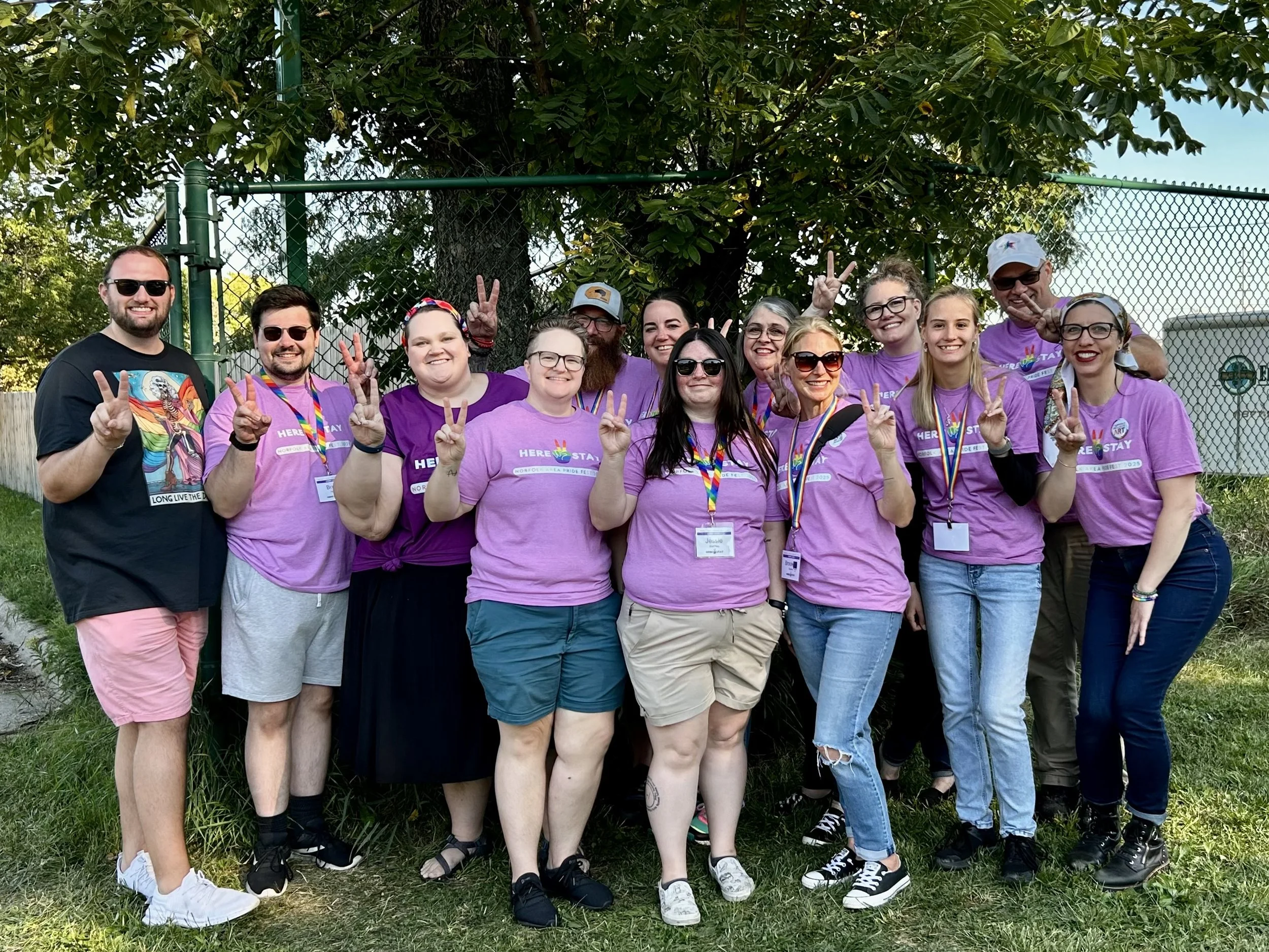 A group of board members and volunteers make the peace sign.
