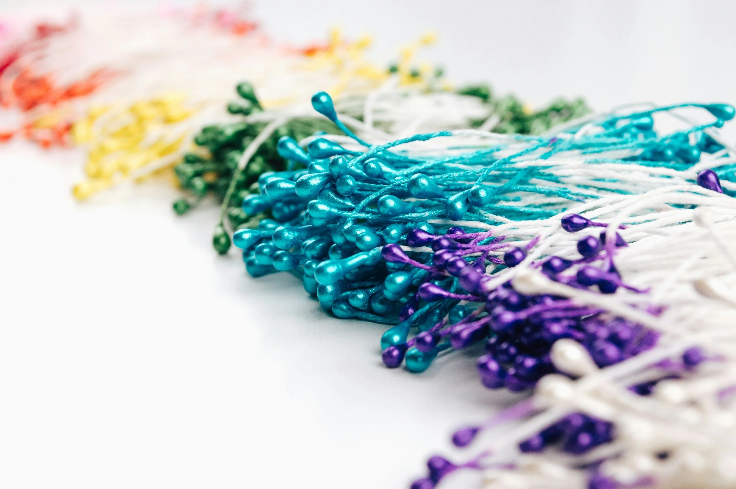 Multicolored string lights in various colors including blue, purple, white, green, yellow, and orange, arranged in a row on a white background.