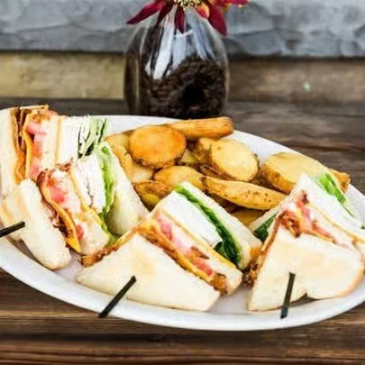 Assorted mini sandwiches with ham, turkey, lettuce, and tomato, along with potato fries on a white platter.