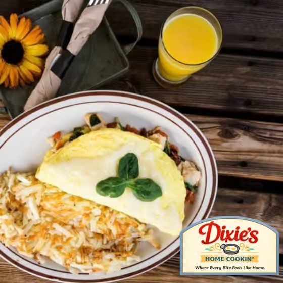 A plate of breakfast food with an omelet, shredded hash browns, and a small salad, next to a glass of orange juice on a dark wooden table, with a small garden flower and a Dixie’s Home Cookin' logo in the corner.