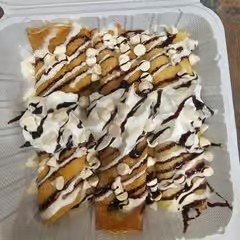 A dessert featuring rolled waffles topped with whipped cream and drizzled with chocolate sauce.