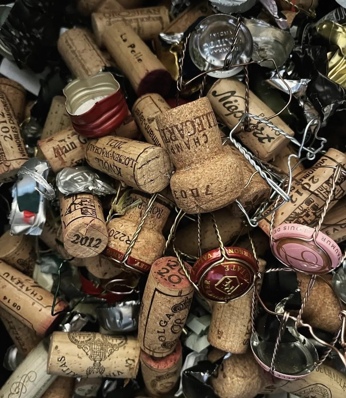 A pile of used champagne corks with some champagne caps and wire cages.