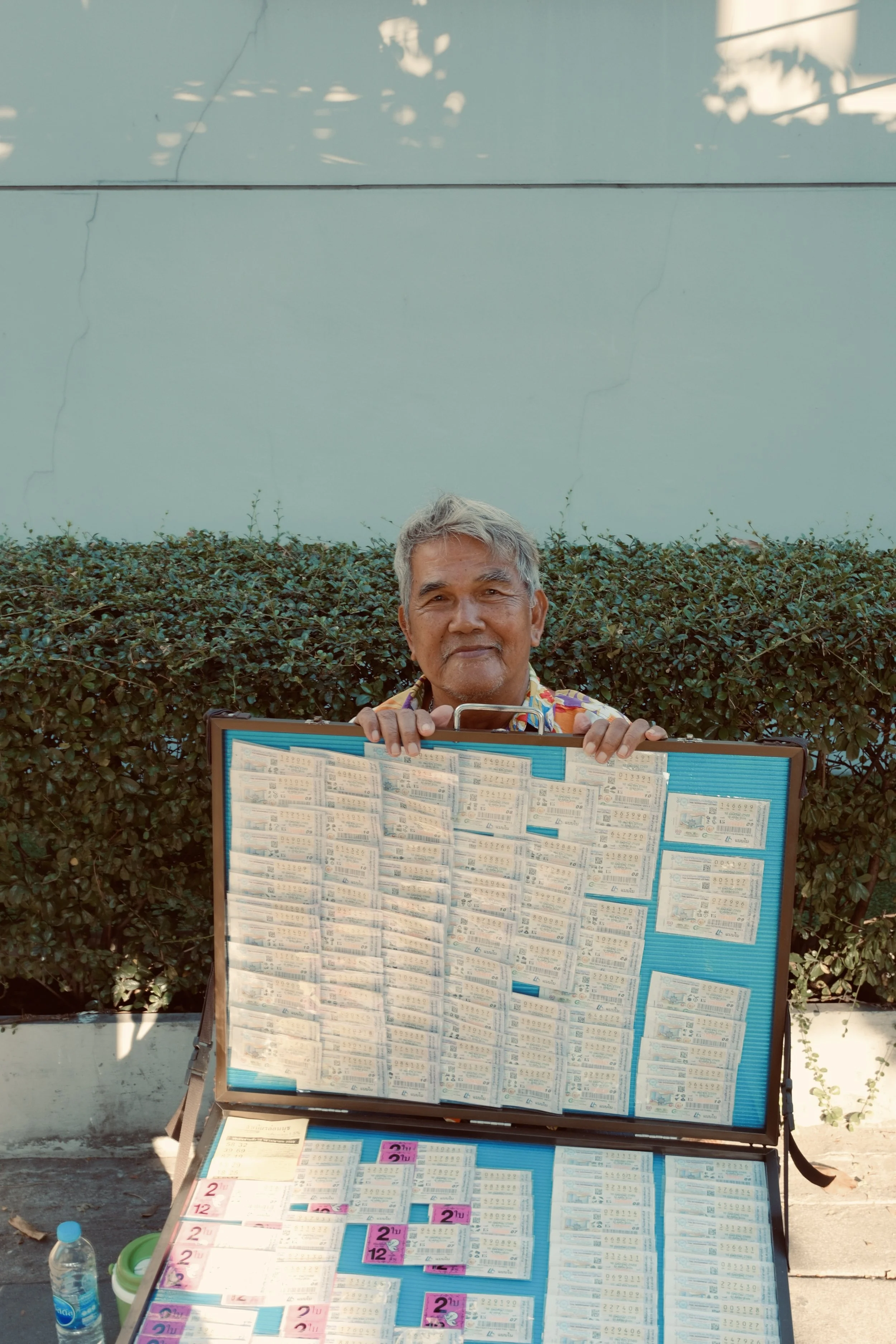 Man displaying a large case of assorted lottery tickets outdoors.