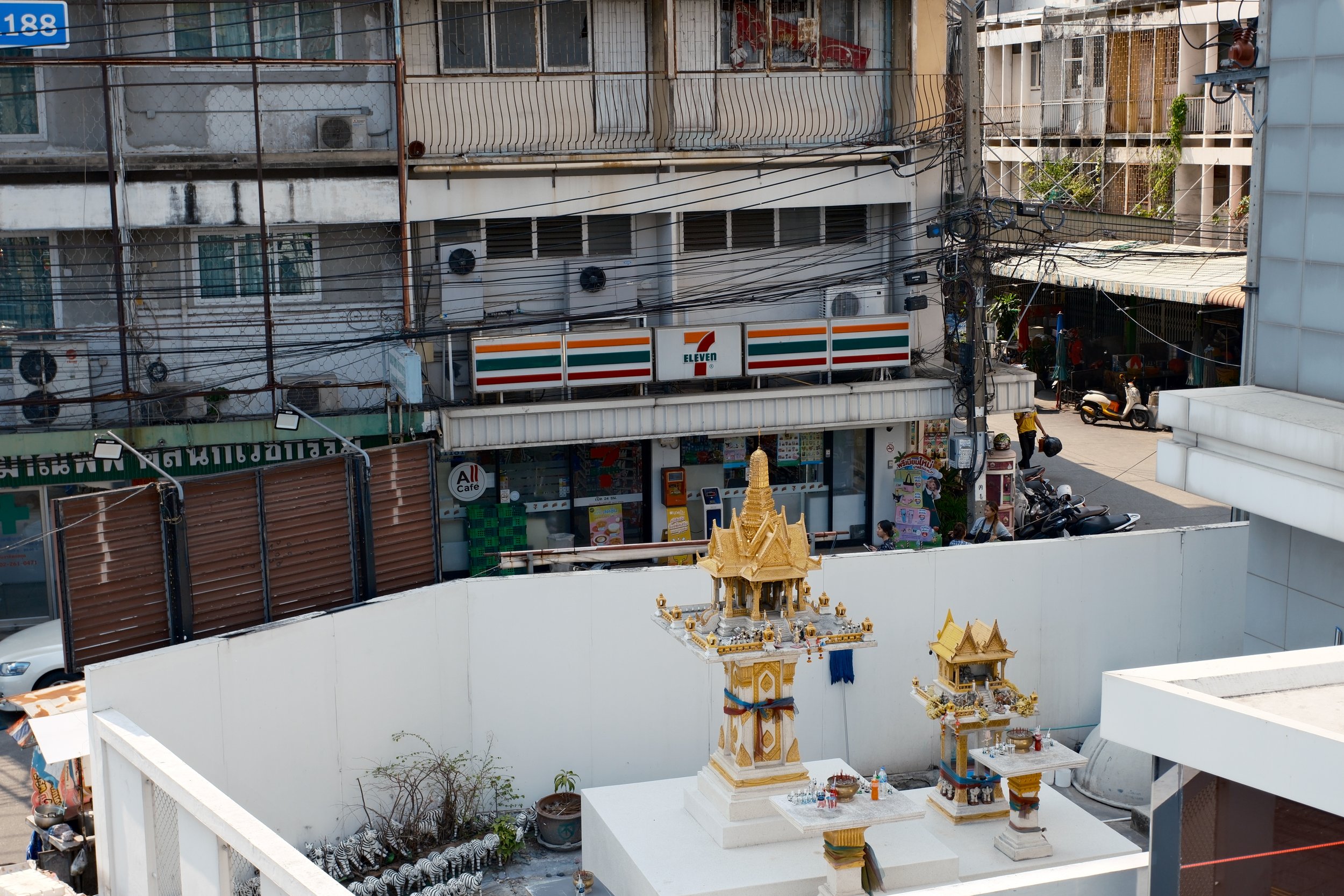 Cityscape with modern skyscrapers, trees, and power lines. The tallest building has a reflective blue glass facade.