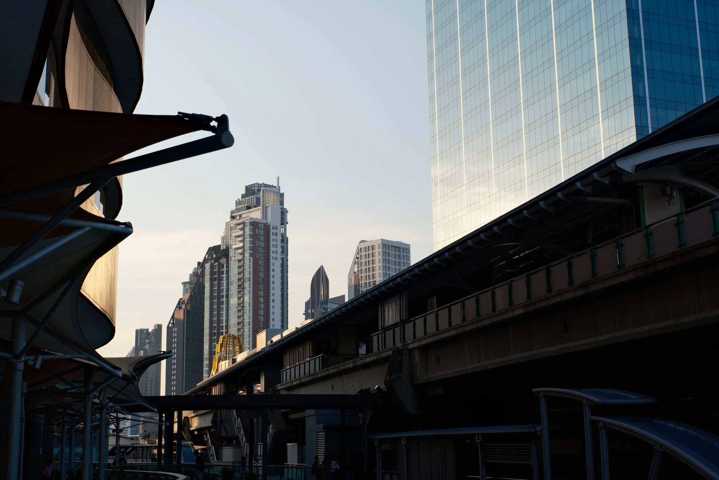 City skyline with tall modern buildings and an elevated train track in the foreground.