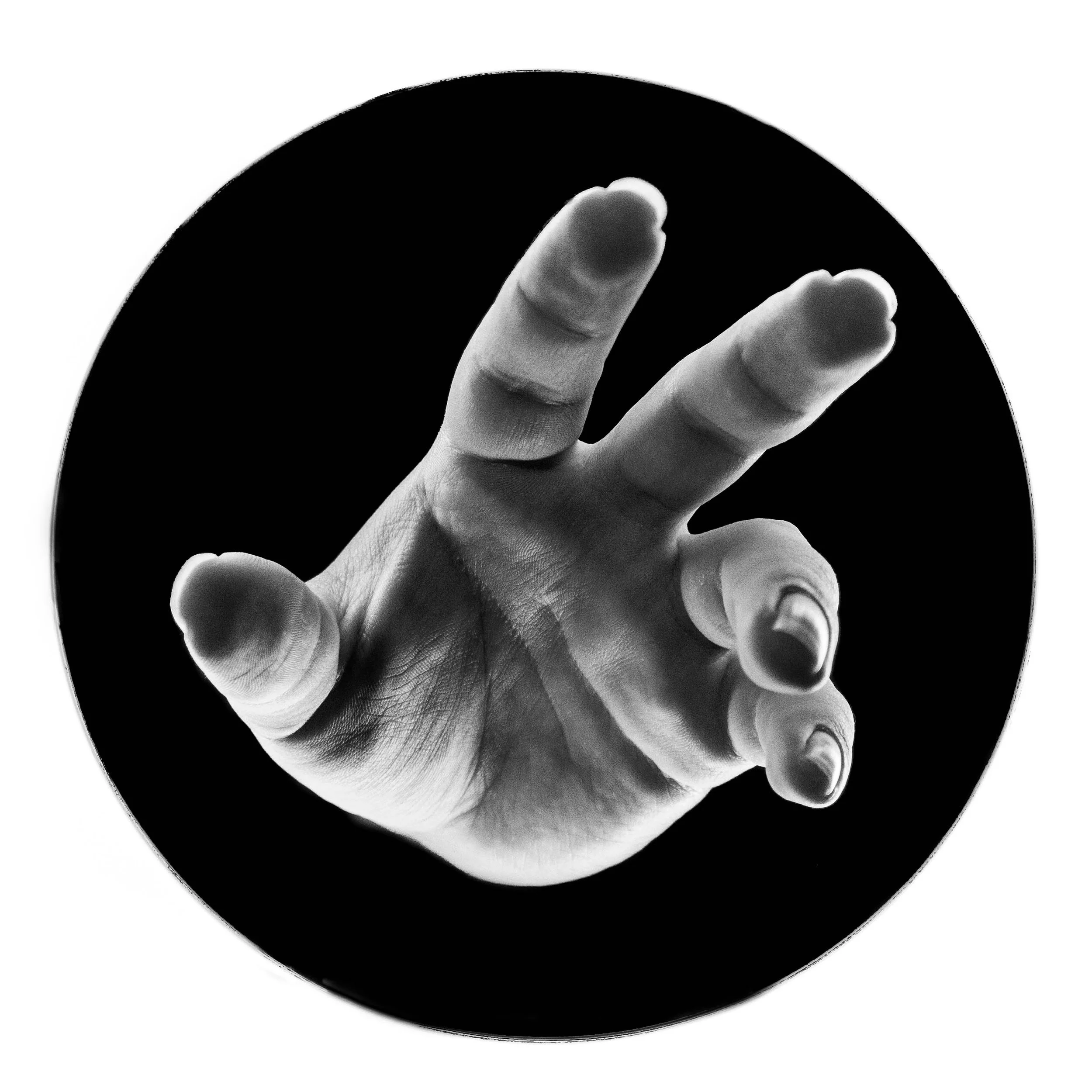 A black and white close-up of a hand reaching out with fingers extended against a dark circular background.
