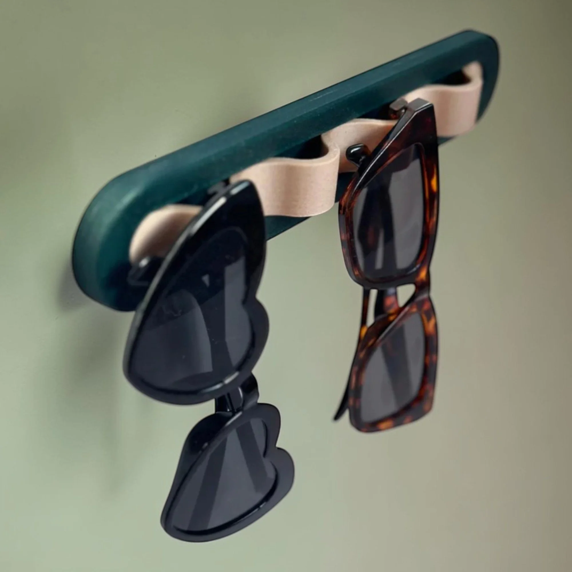 Sonnenbrillenhalter in Dunkelgrün und Beige mit zwei aufgehängten Sonnenbrillen, praktisch als moderne Wandaufbewahrung im Flur oder Ankleidebereich.