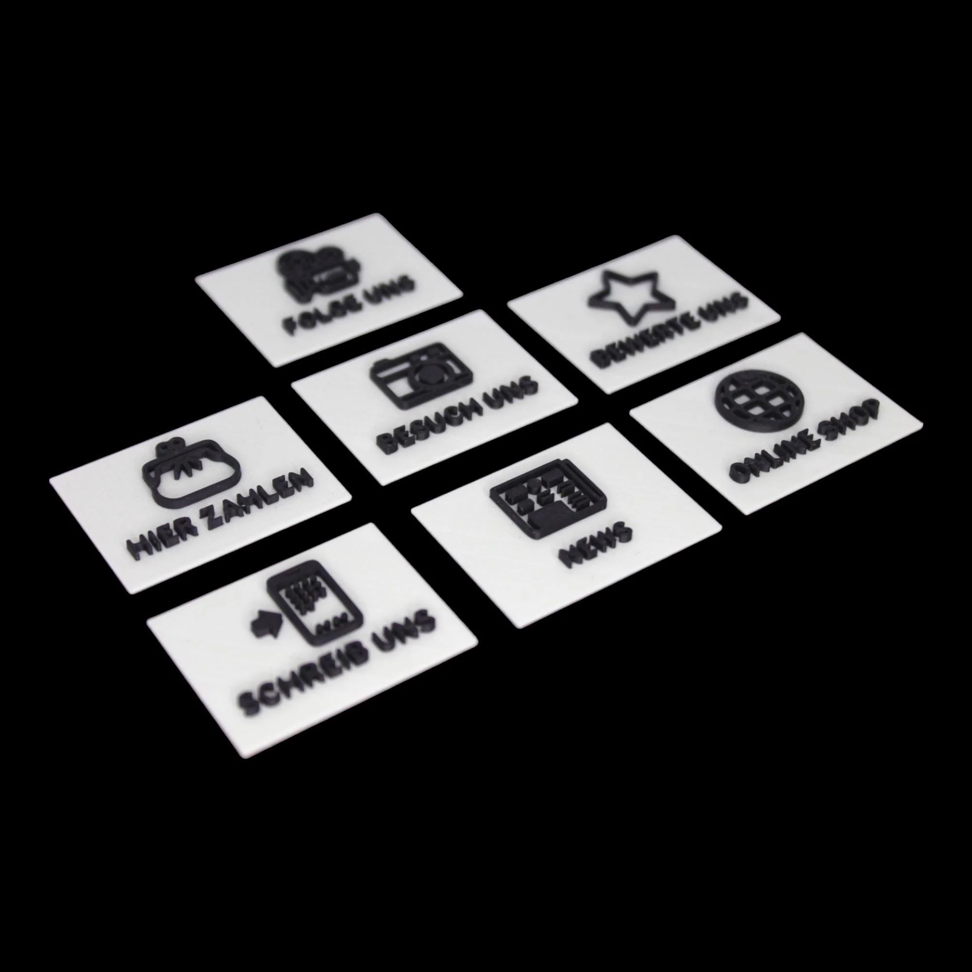 Set mit sieben austauschbaren Inlays für den NFC-Aufsteller auf schwarzem Hintergrund, mit Symbolen für Zahlung, Social Media, Kontakt und Shop.