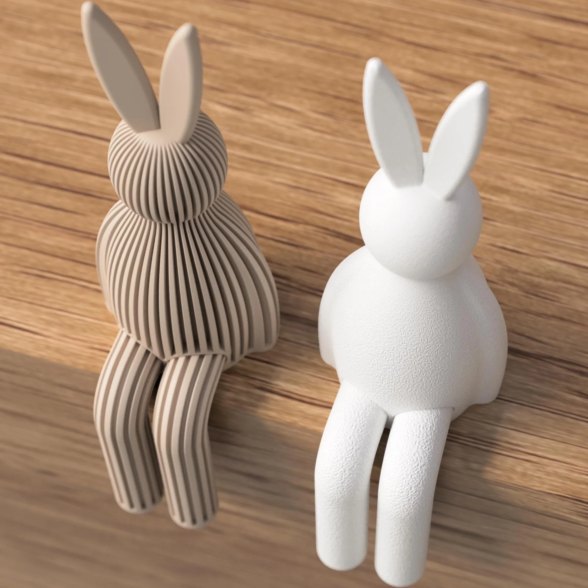 Sitzender Japandi Osterhase in Taupe und Weiß als Farbvergleich, links gerippt und rechts glatt, mit hängenden Beinen auf Holzoberfläche.