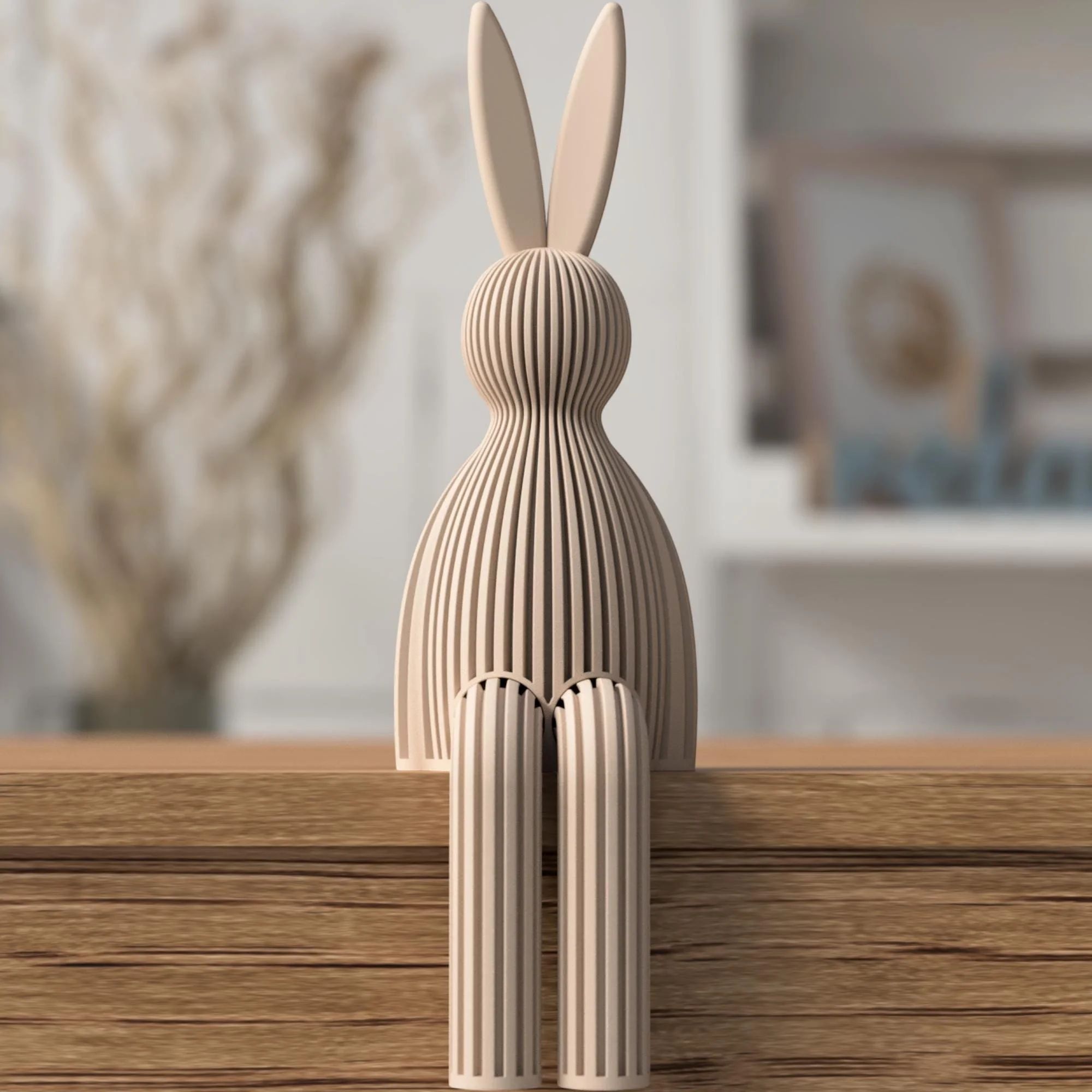 Gerippter Osterhase in Taupe als sitzende Dekofigur mit langen Ohren und hängenden Beinen auf einer Holzkante vor ruhigem Wohnhintergrund.