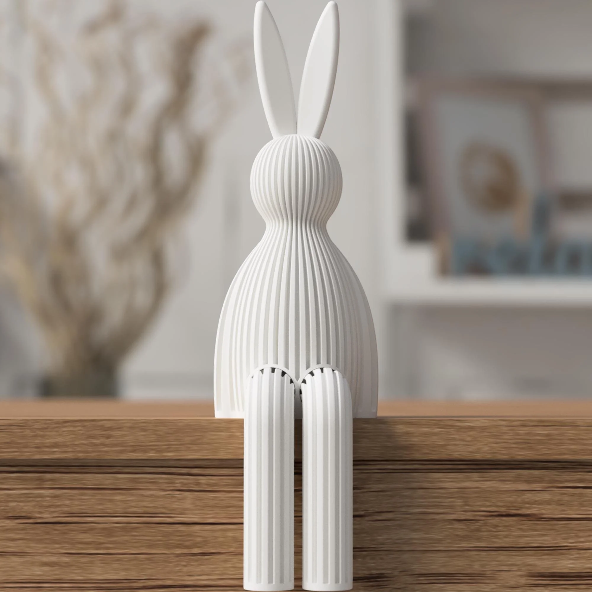 Weiße Osterfigur mit gerippter Oberfläche und langen Ohren, sitzend auf einer Holzkante vor unscharfem Wohnhintergrund.