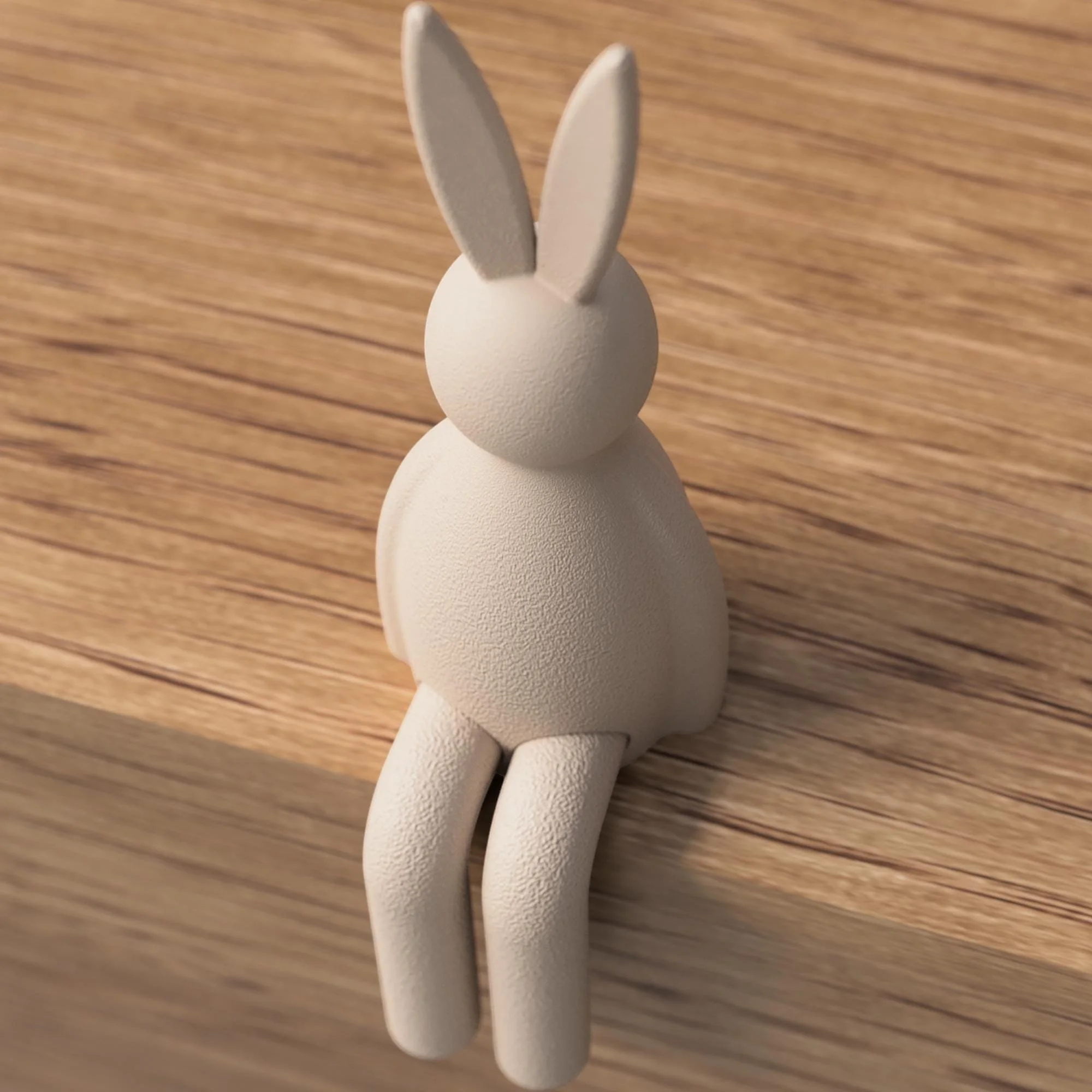 Cremefarbener Osterhase mit glatter Oberfläche als sitzende Figur auf Holz, reduziert gestaltet mit langen Ohren und hängenden Beinen.