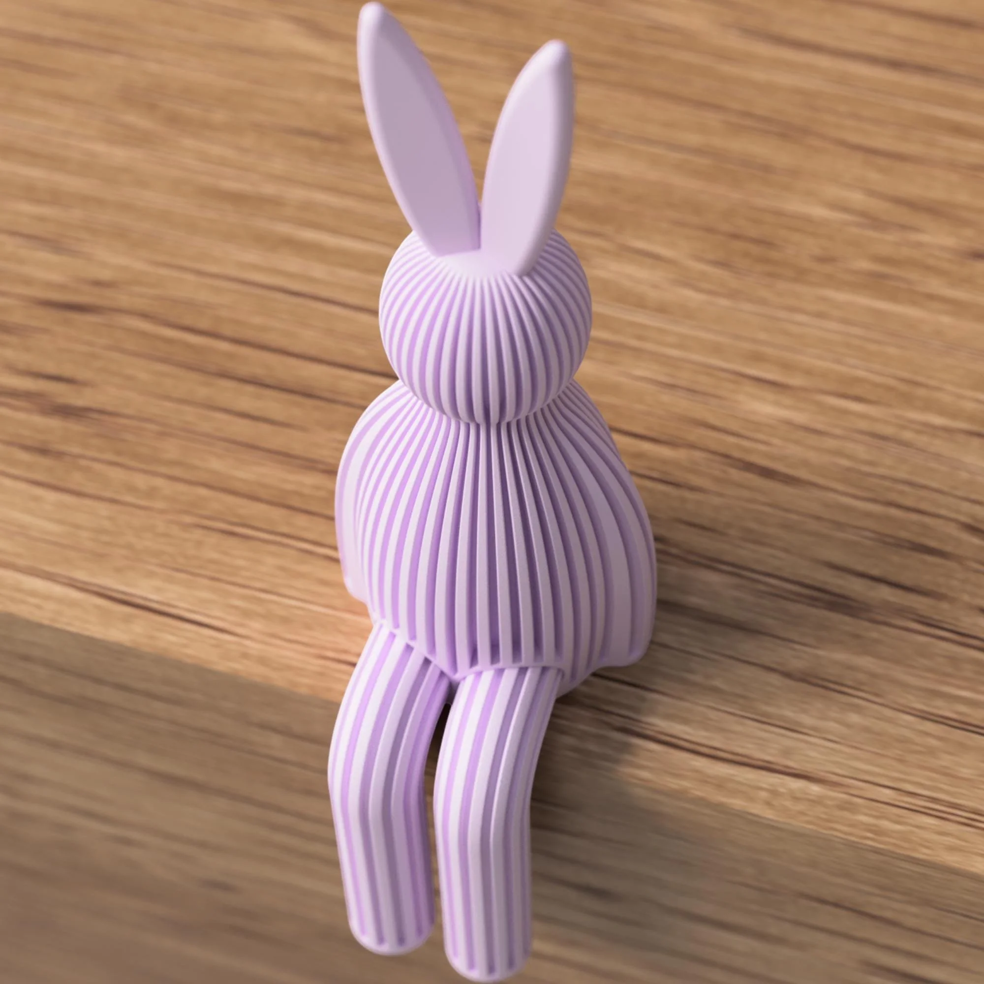 Fliederfarbene Sitzfigur in Hasenform mit gerippter Oberfläche auf Holz, moderne Osterdeko mit langen Ohren und hängenden Beinen.