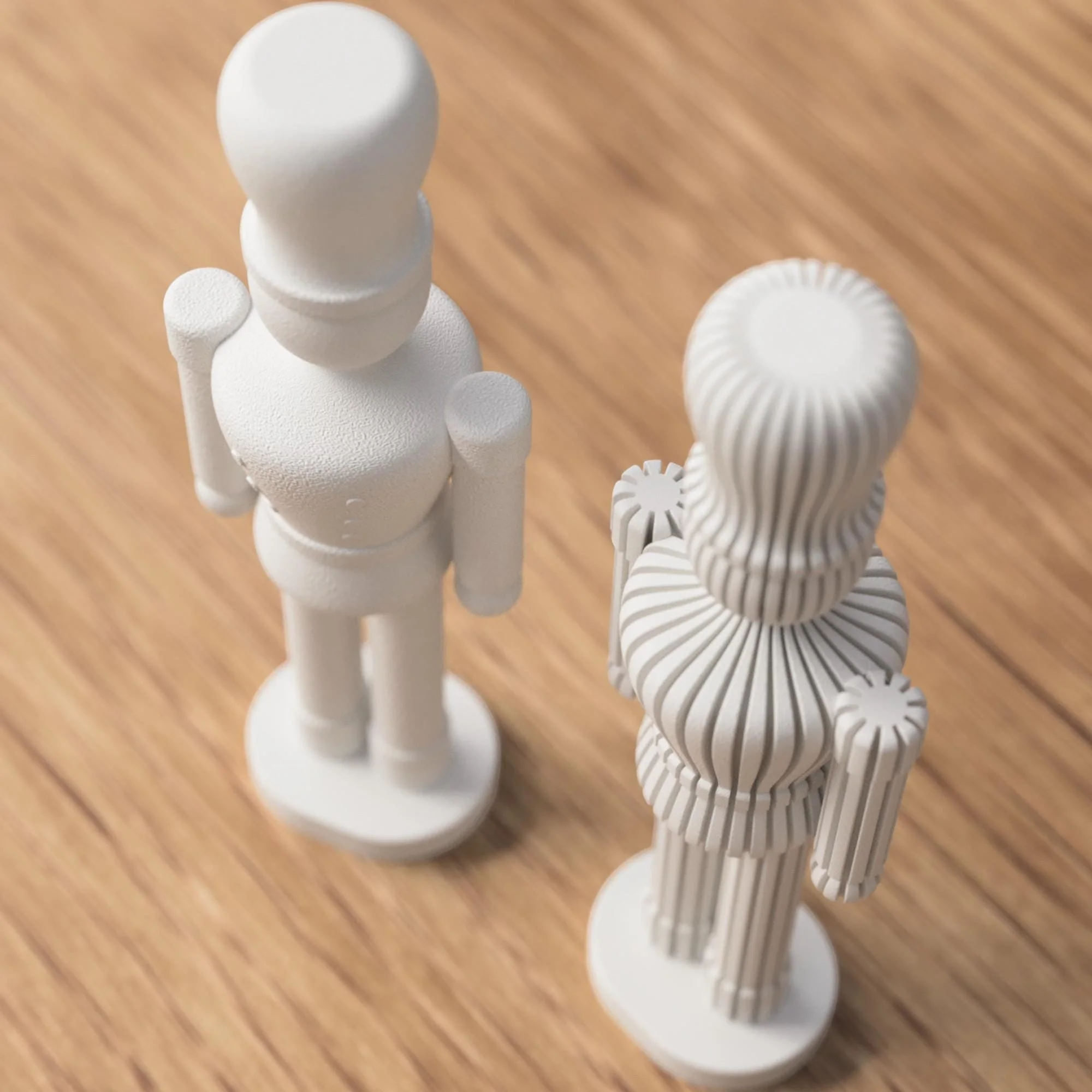 Weißer Nussknacker und beige gerippte Variante schräg von oben, mit gut sichtbarer Rückseite und plastischer Form auf Holzfläche.