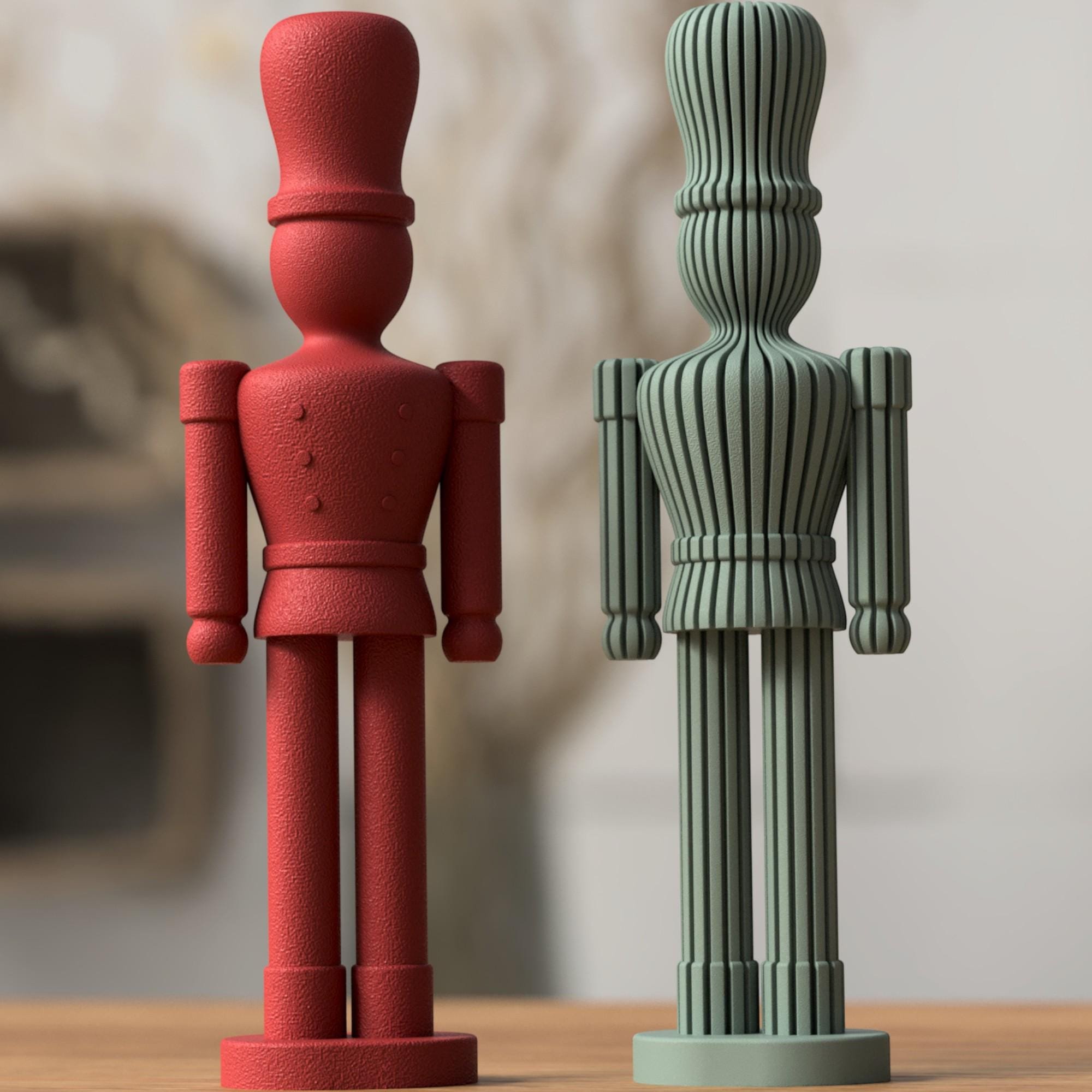 Moderner Nussknacker in Rot neben einer salbeigrünen Variante mit gerippter Oberfläche, frontal auf Holzfläche vor weichem Hintergrund.