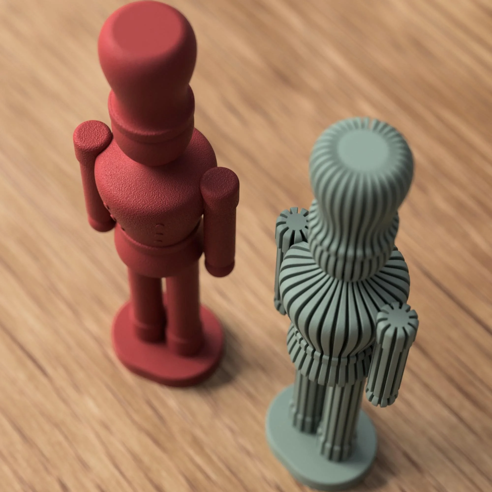 Moderner Nussknacker in Rot neben einer salbeigrünen Variante mit gerippter Oberfläche, frontal auf Holzfläche vor weichem Hintergrund.