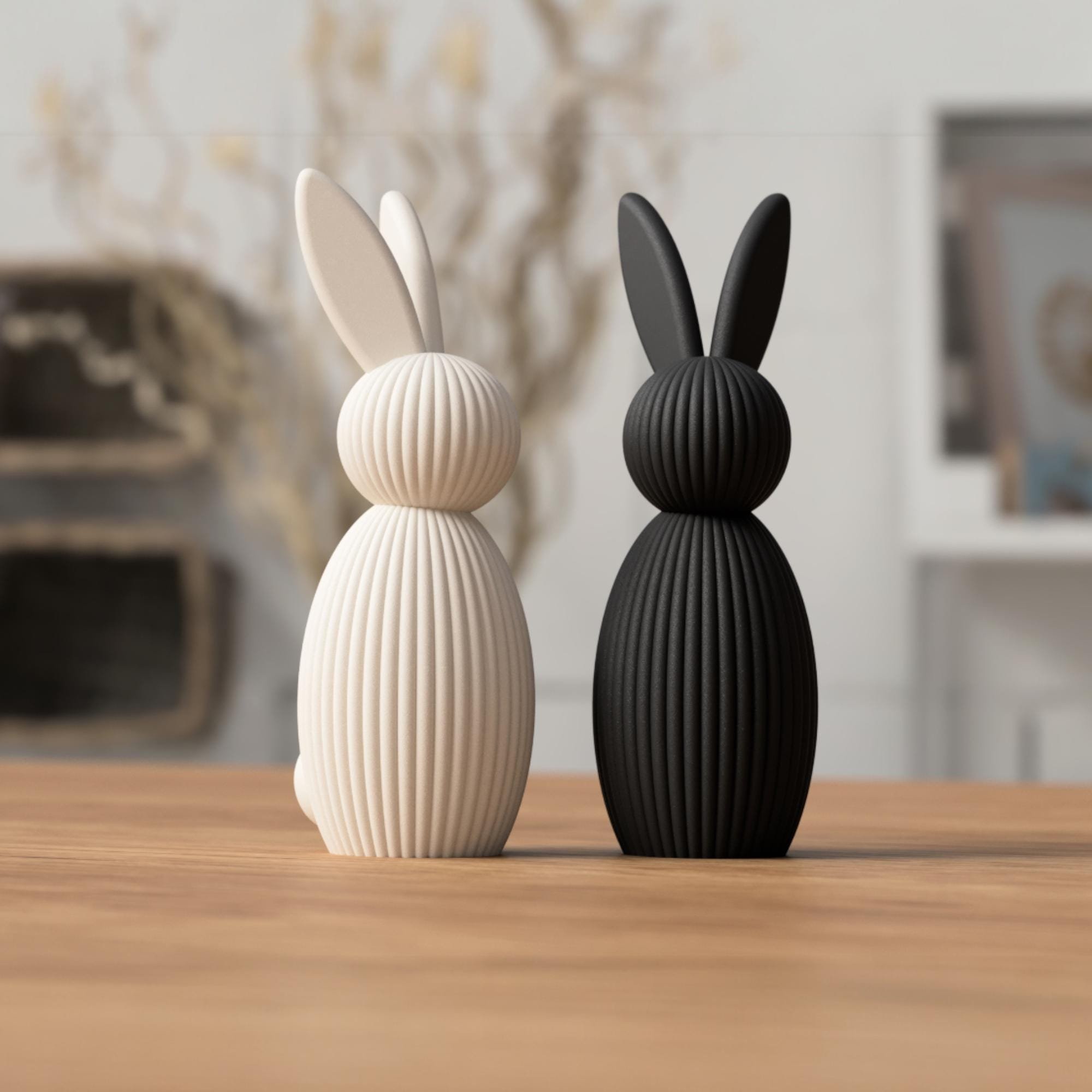 Minimalistische Hasenfigur in Creme und Schwarz nebeneinander auf Holzfläche, als moderne Osterdeko in zwei schlichten Farbvarianten.